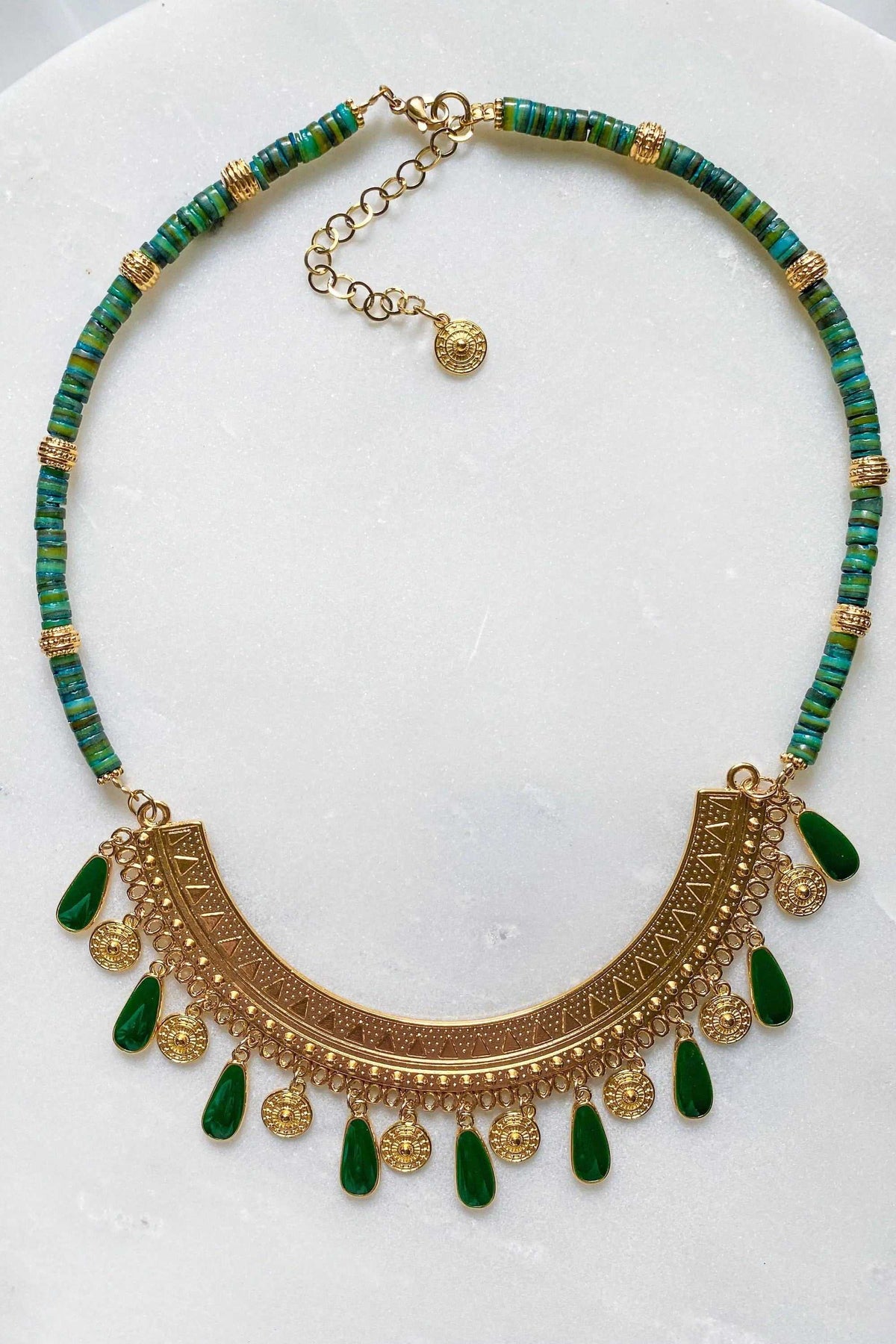Boho chic necklace with teal and green beads, an ornate gold-tone filigree crescent pendant and dangling charms