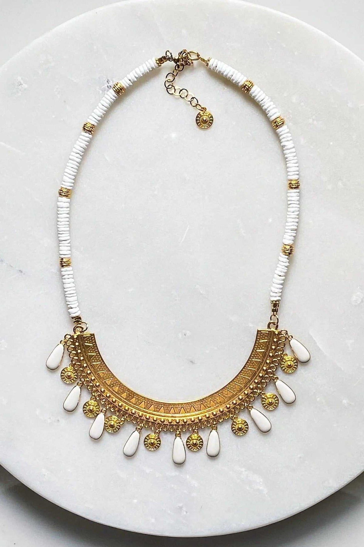 Boho chic necklace with white shell beads, gold-tone metalwork, and a statement pendant with dangling charms