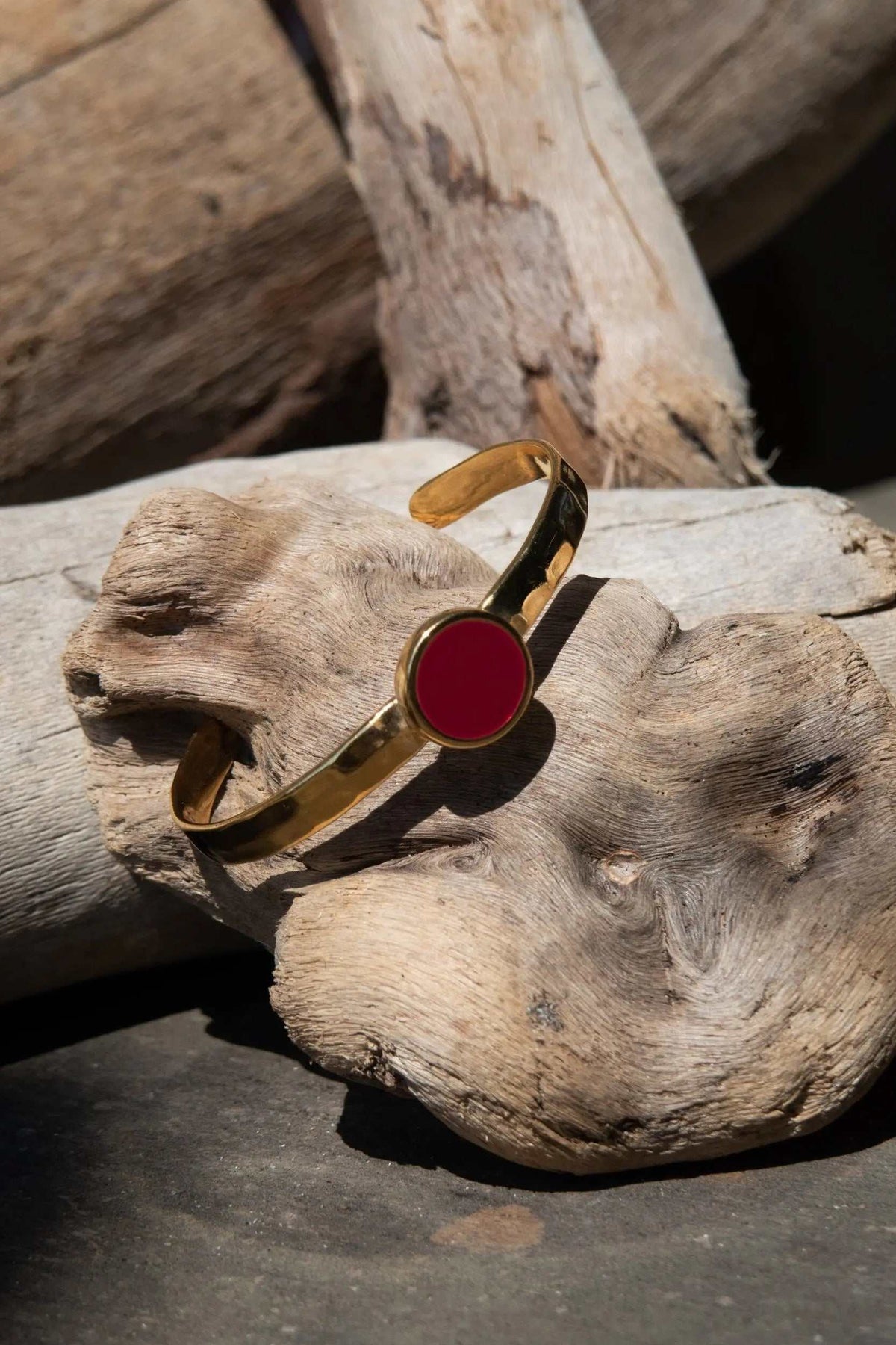 Bracelet femme or en métal doré avec une large pièce circulaire rouge en résine et une bande martelée ajustable