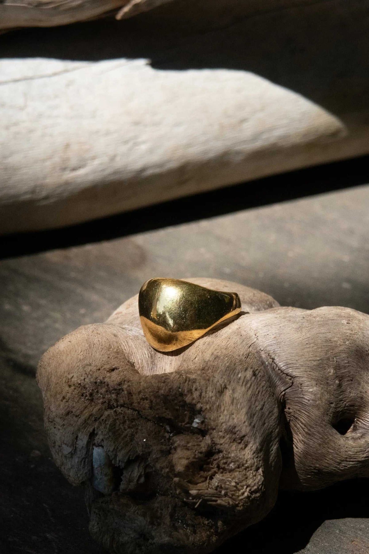Chunky bold RING in polished gold-plated brass, featuring a smooth, broad sculptural face and an adjustable band.