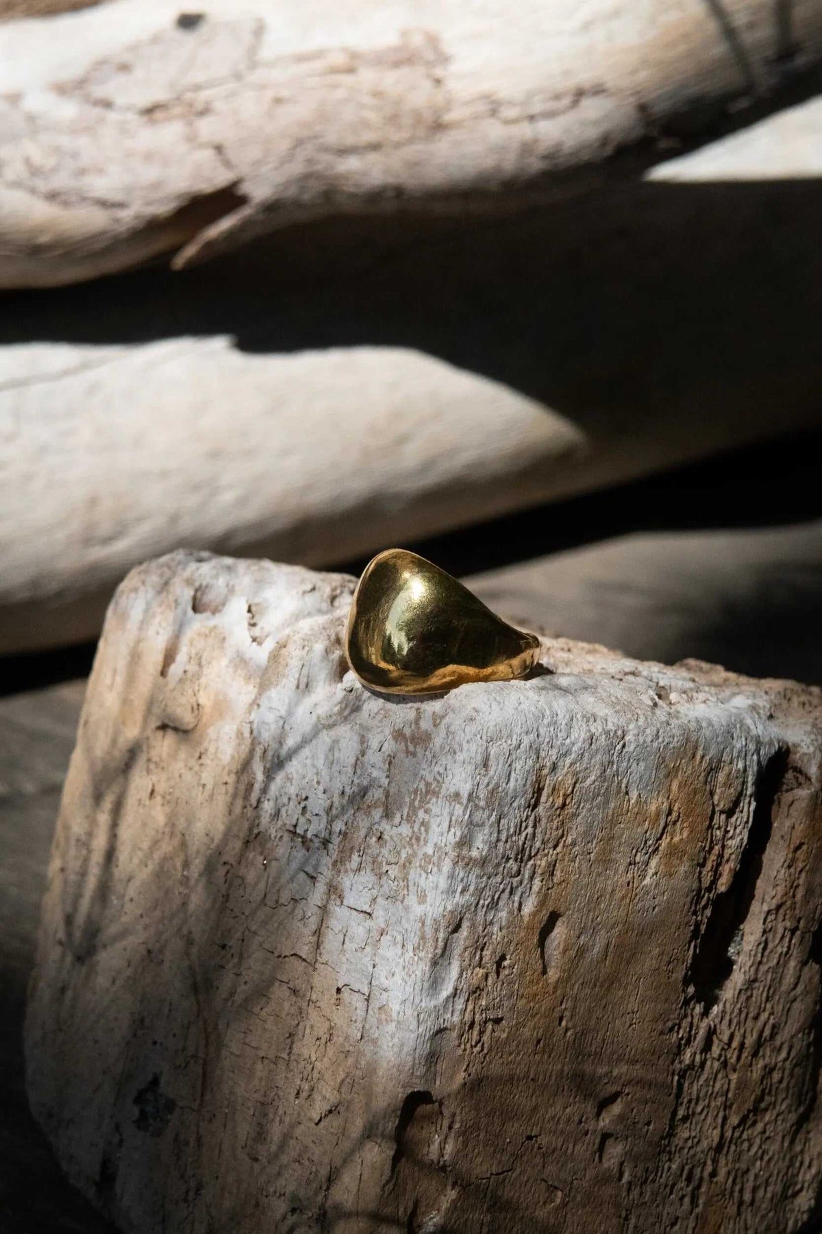 Chunky bold RING in polished gold-tone metal with a sculptural rounded triangular form and smooth surface
