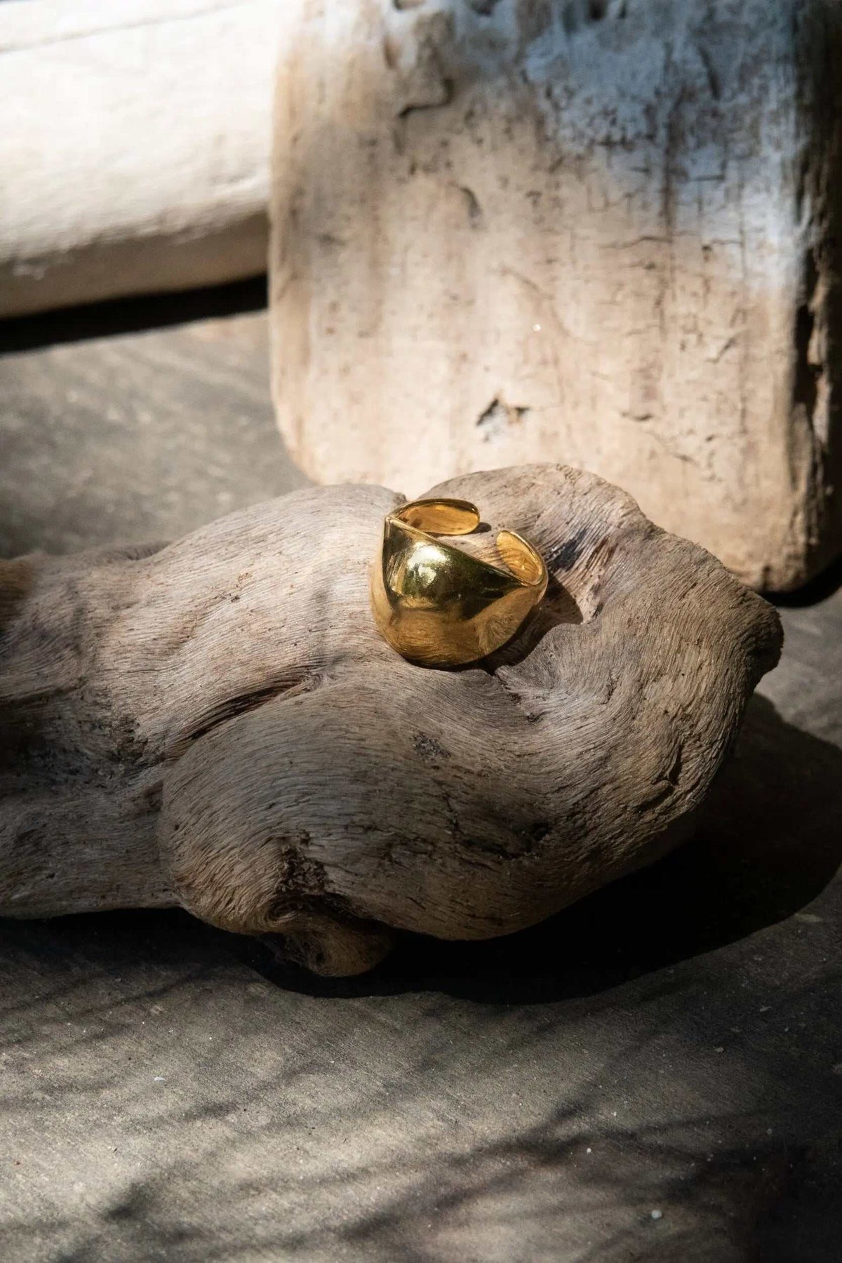 Chunky bold RING in polished gold-tone metal, featuring a wide sculptural band with a rounded, faceted face