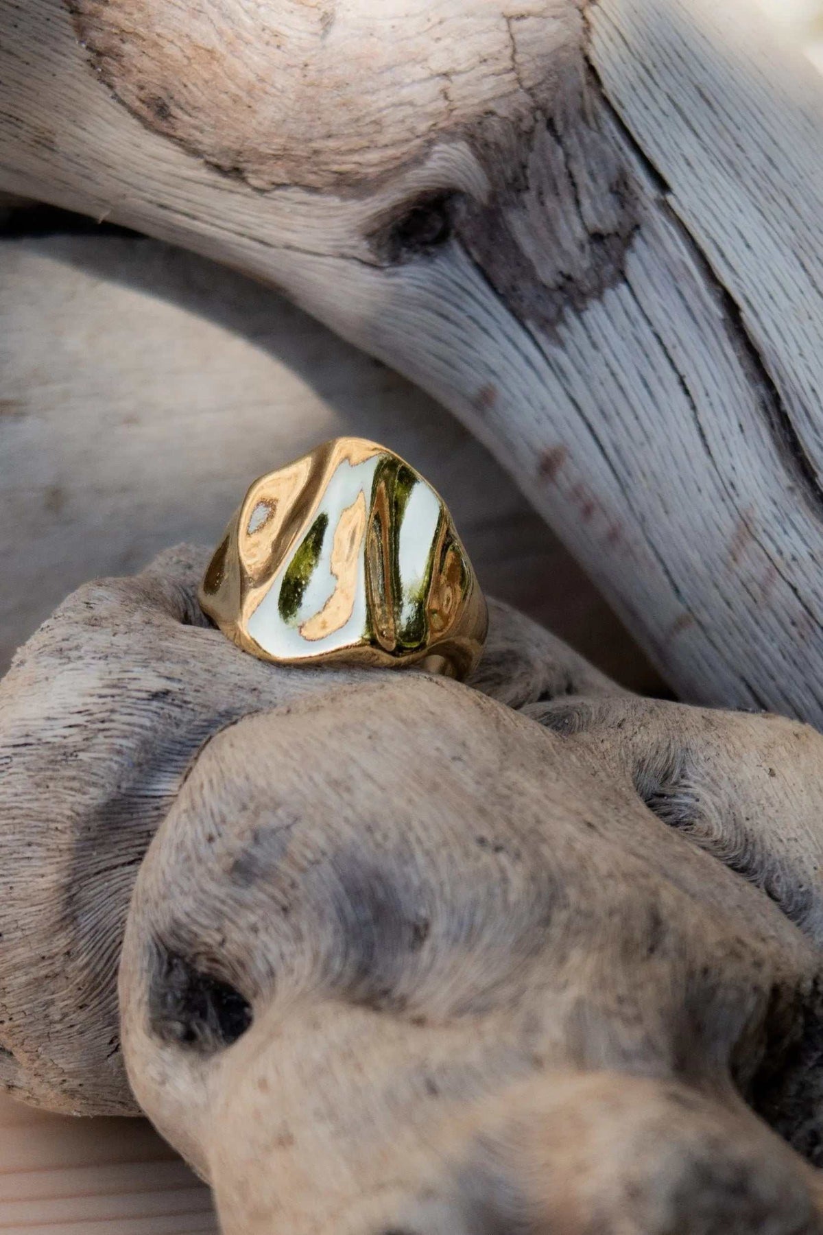 Chunky ring in polished gold-tone metal with an organic sculpted surface and flowing wave-like ridges