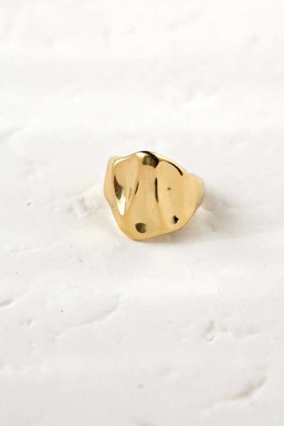 Chunky ring in polished gold-tone metal with a wide, irregular sculpted face and softly wavy edges