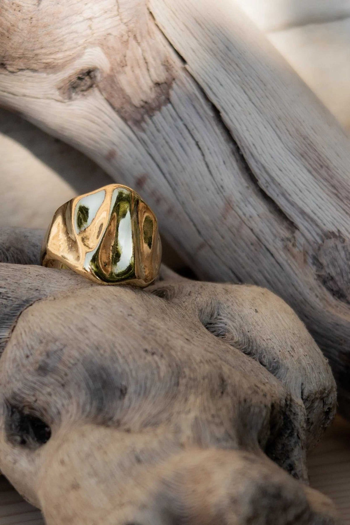 Chunky ring in polished gold-tone metal with a bold, irregular wavy surface and sculptural contours