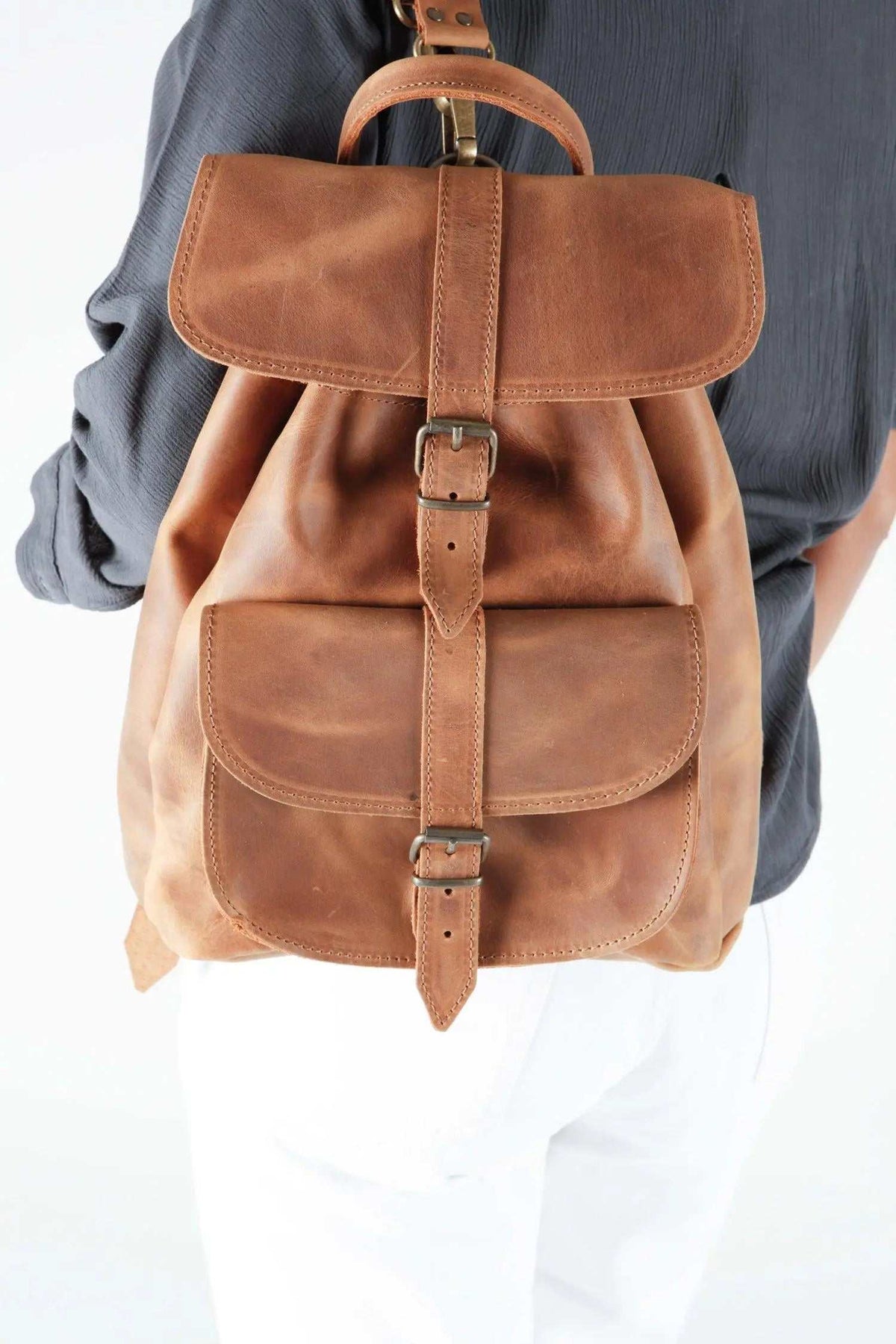 classy leather backpack in warm brown with a smooth leather finish, two flap pockets and buckled straps