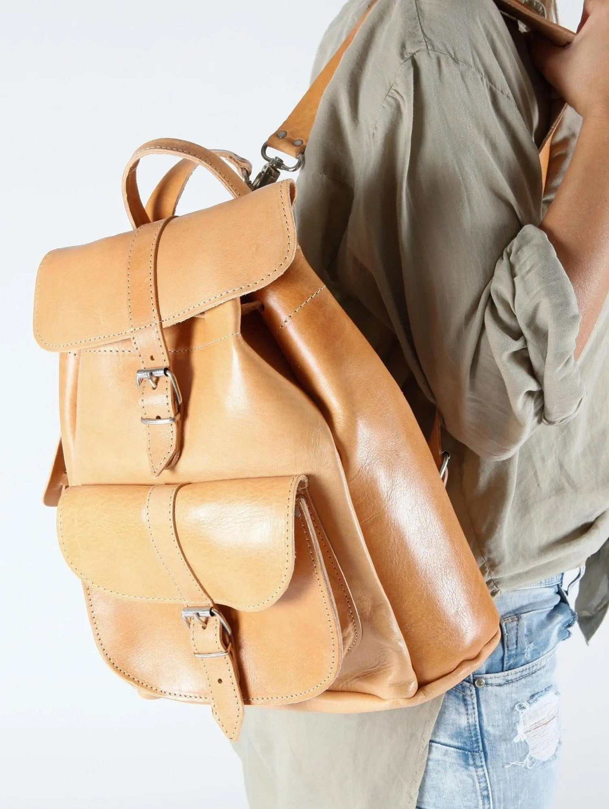 classy leather backpack in tan leather with a drawstring top, buckled flap and roomy front pocket