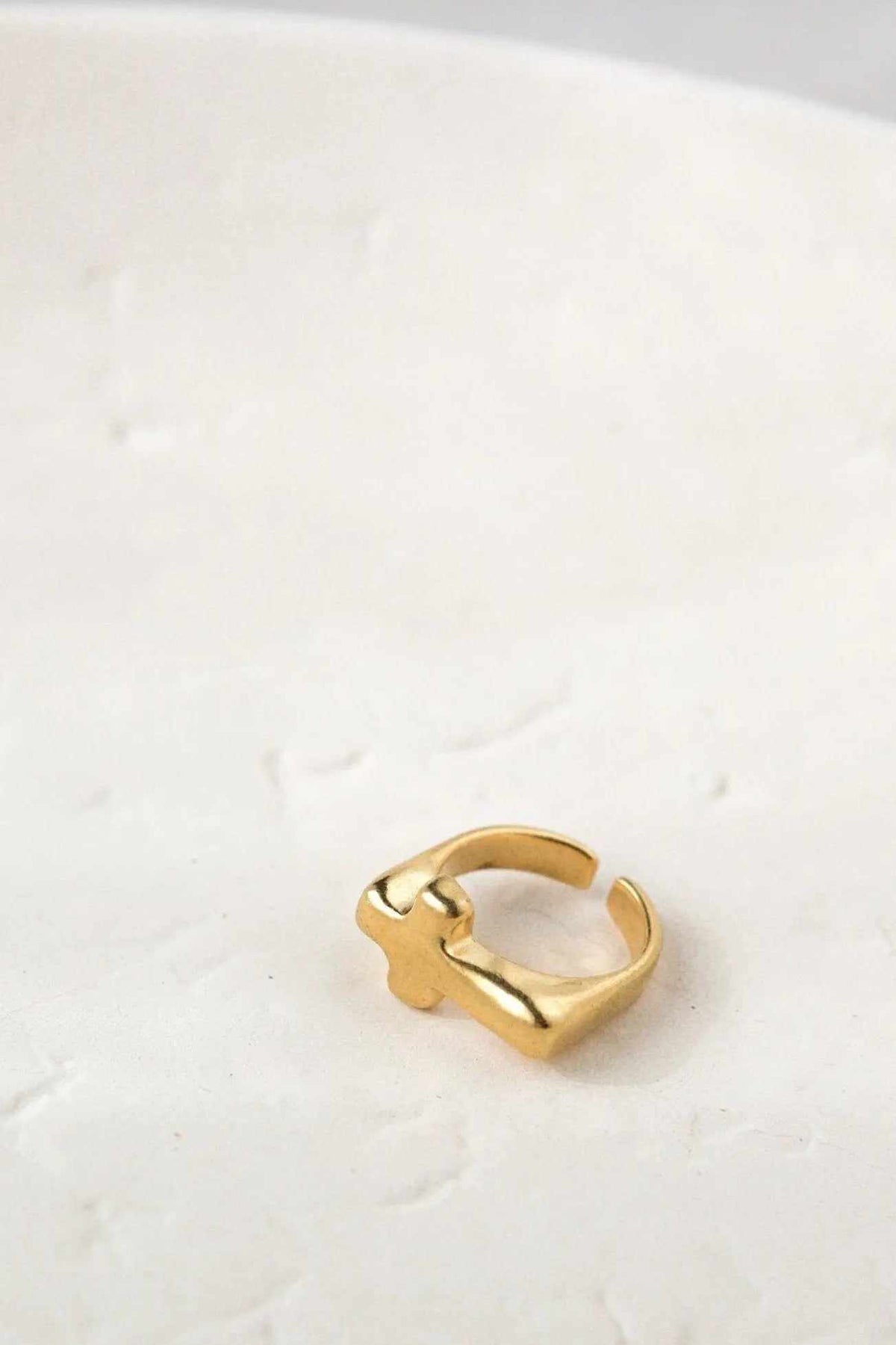 Cross RING in gold-tone metal with an adjustable open band and sculptural crossed detail at the front