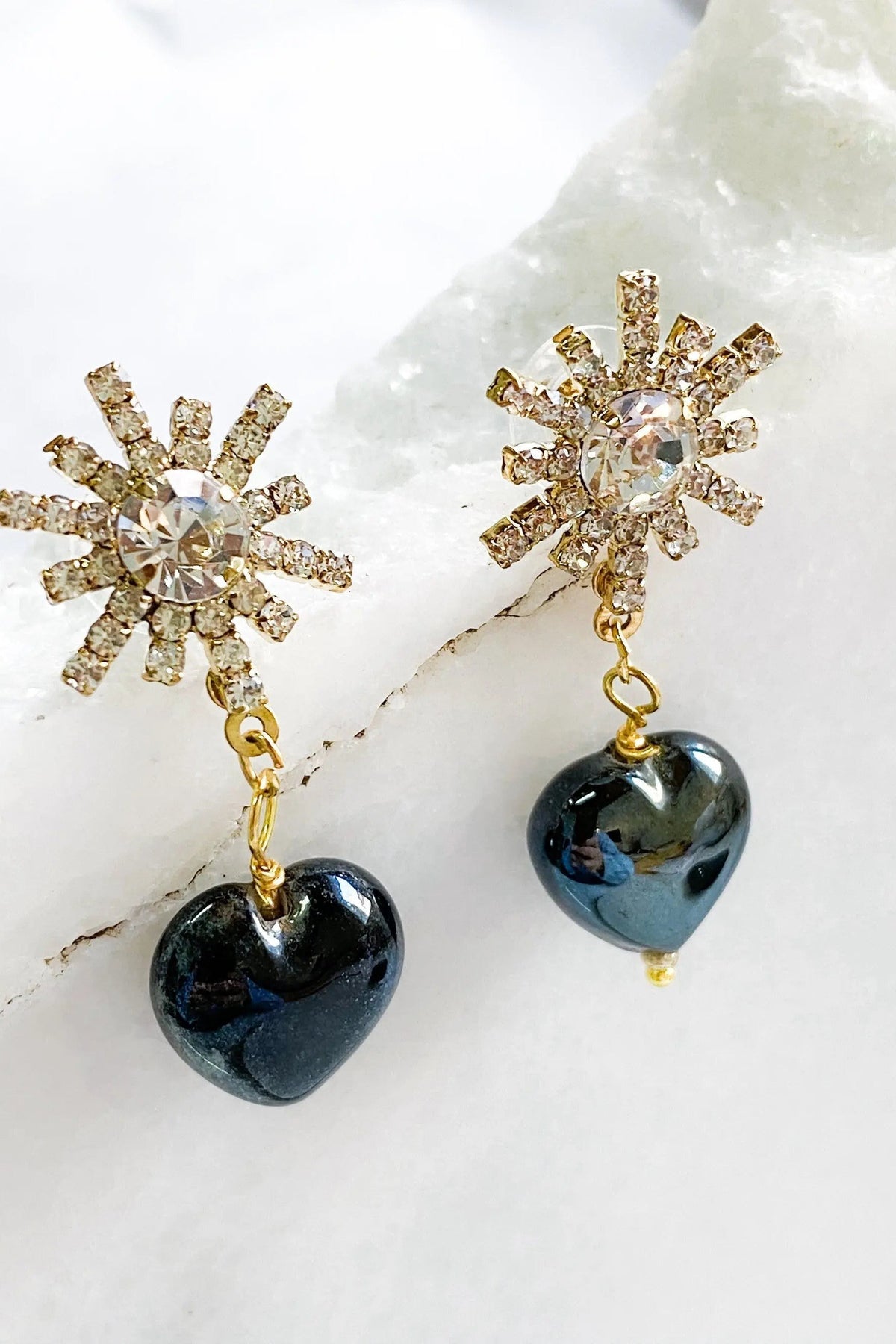 Crystal star earrings in gold-tone crystal bursts with glossy black heart-shaped drop charms