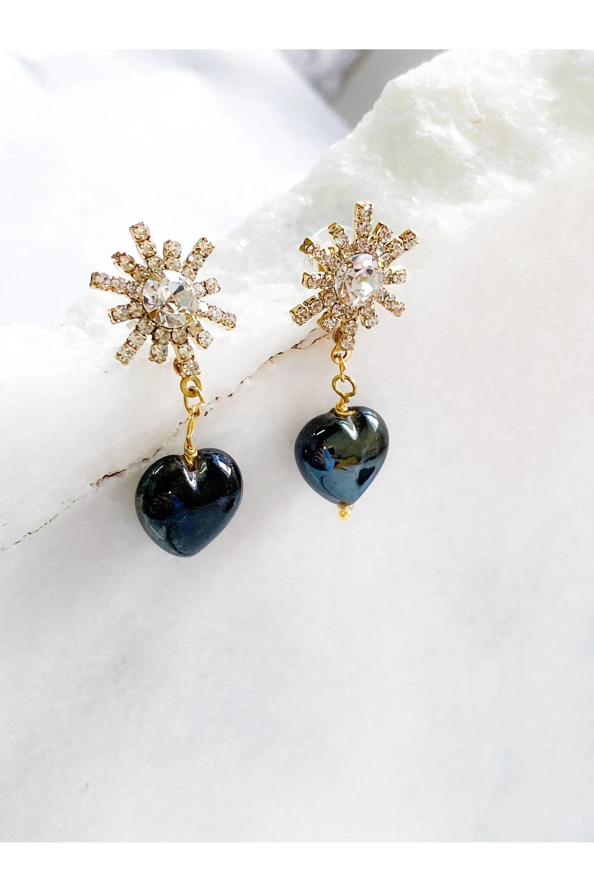 Crystal star earrings with gold-tone crystal bursts and glossy black heart charms dangling below