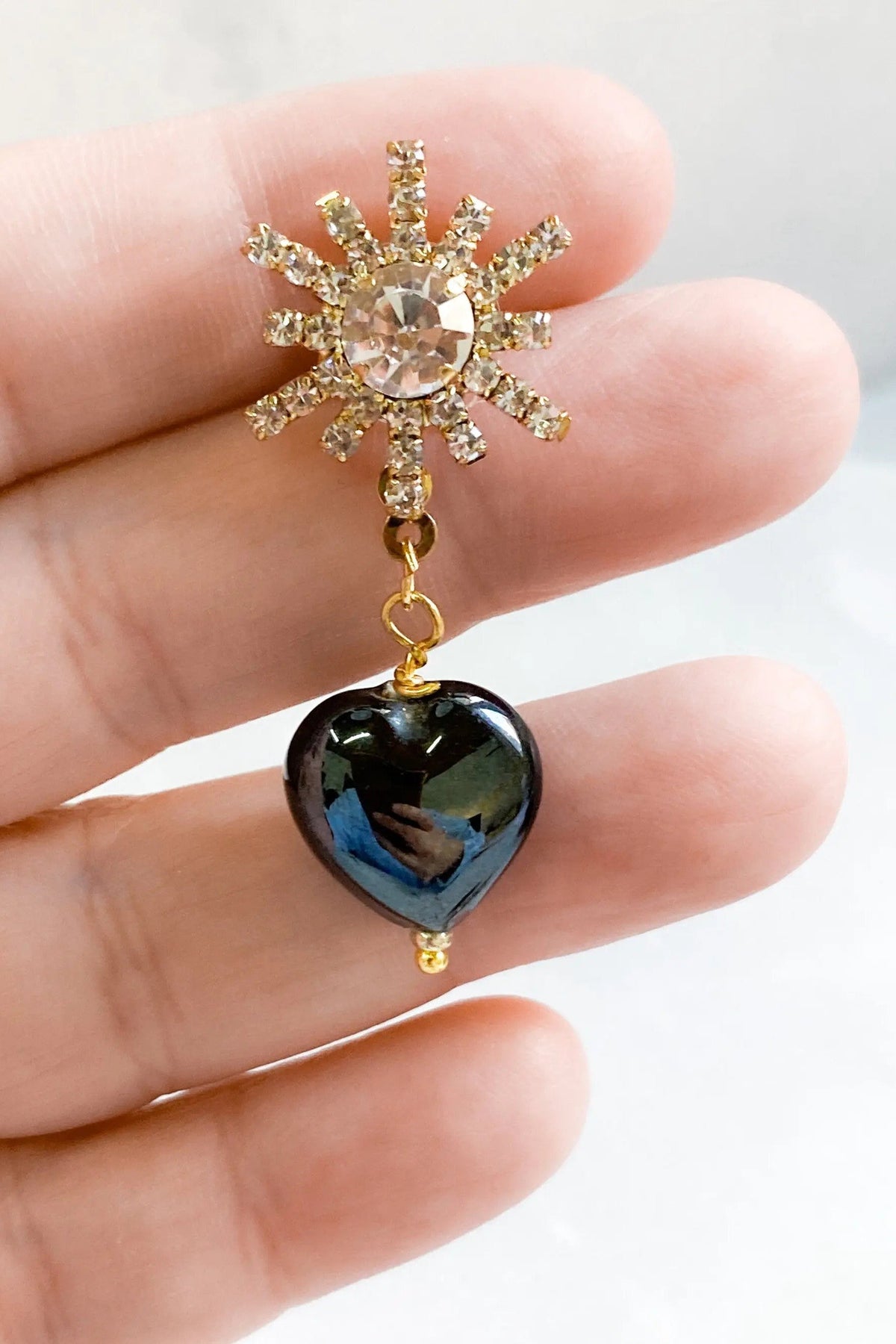 Crystal star earrings in gold-tone metal with clear rhinestones and a dangling glossy black heart charm
