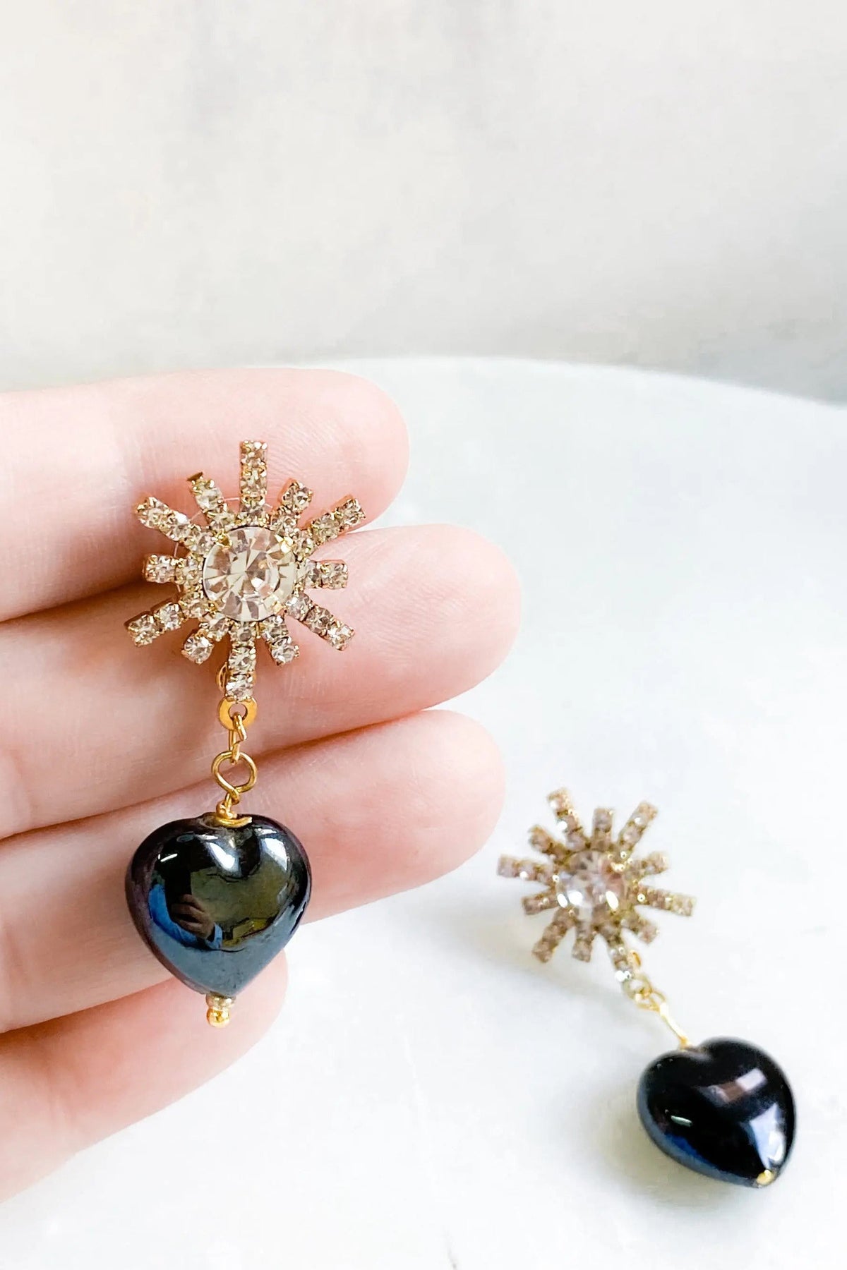 Crystal star earrings with gold-tone rhinestone bursts and glossy black heart-shaped drops