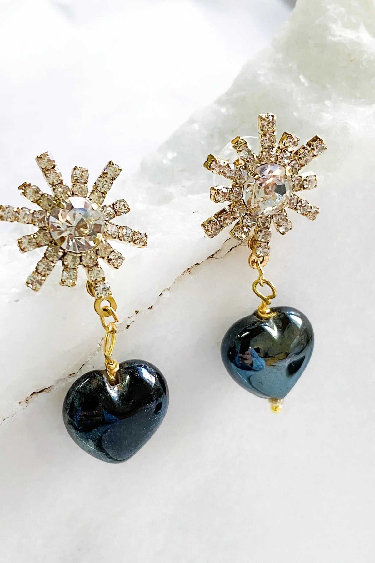 Crystal star earrings with gold-tone rhinestone bursts and glossy black heart-shaped dangling charms