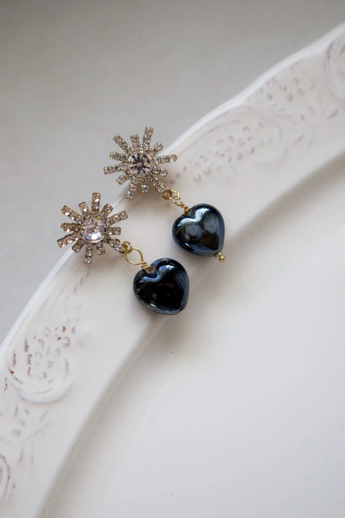 Crystal star earrings with gold-tone rhinestone starbursts and glossy black heart charms dangling below