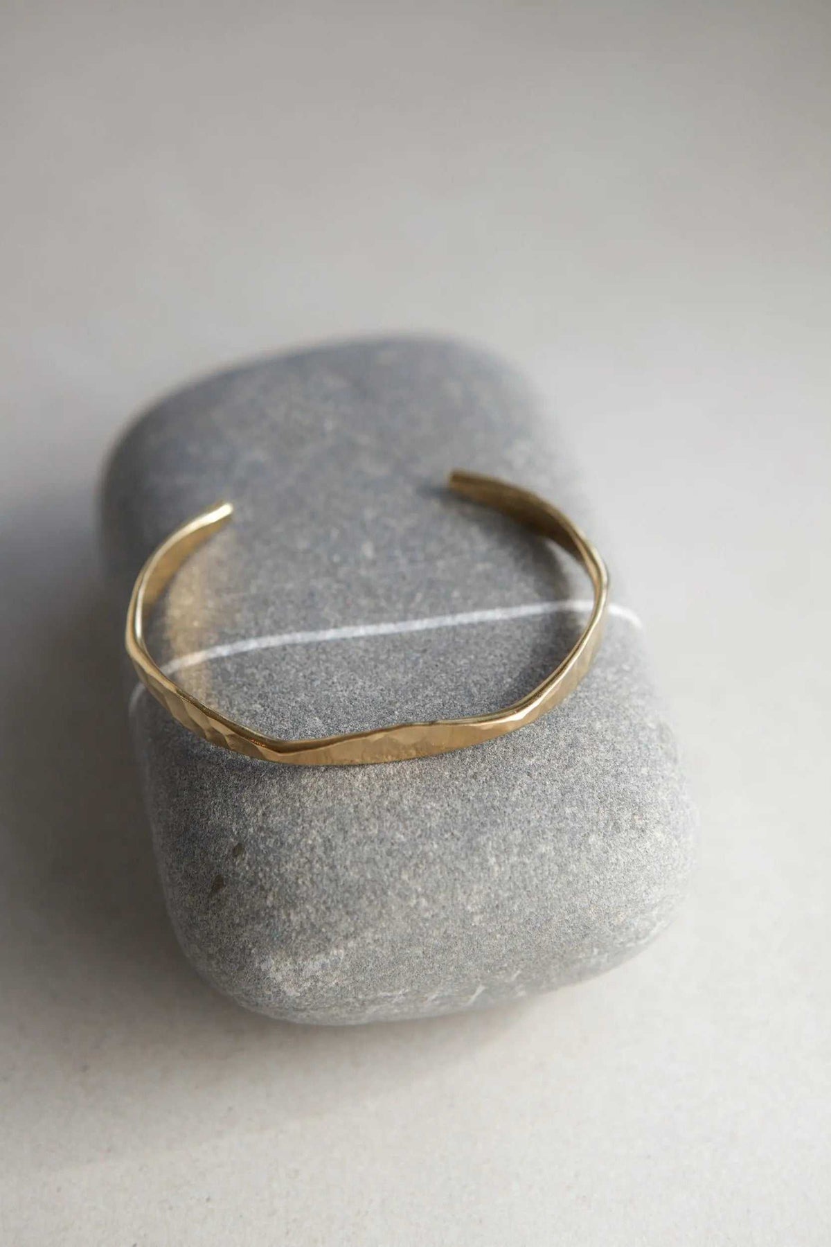Delicate Hammered Bracelet in gold-toned metal, with a slim, uneven hammered open cuff design.