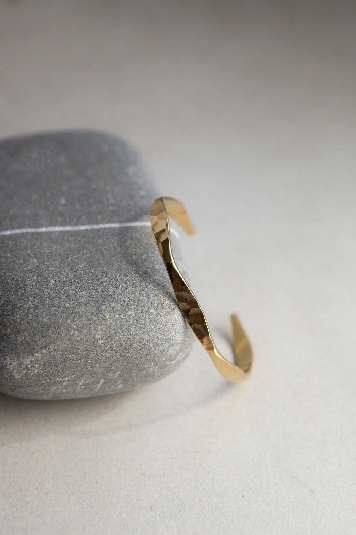 Delicate Hammered Bracelet in gold-tone metal, featuring a slim open cuff with an uneven, faceted hammered finish