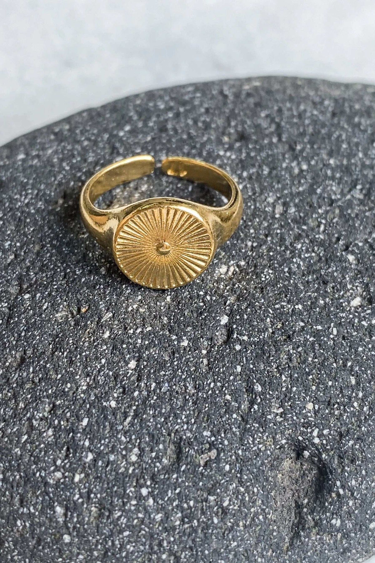 DELOS RING in gold-tone metal with a round sunburst medallion and an open, slightly adjustable band