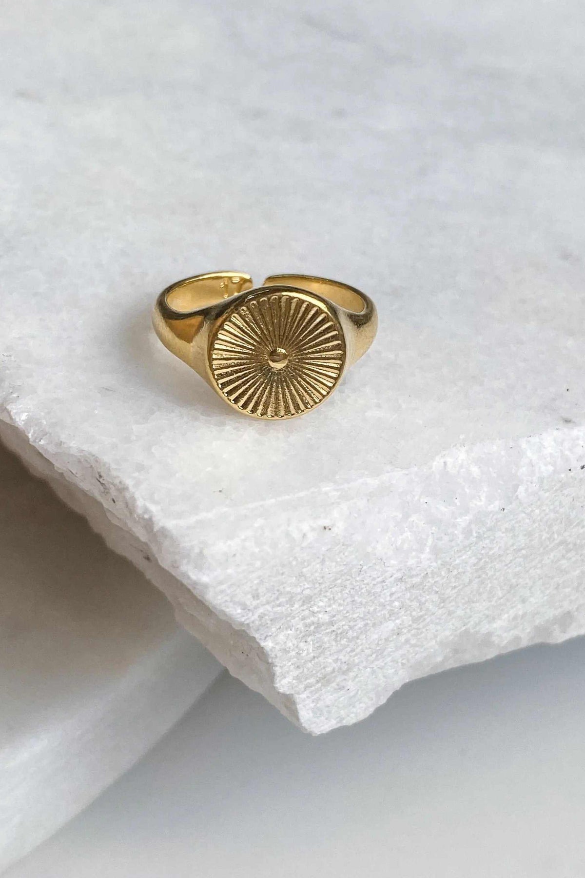 DELOS RING in gold-tone metal with a round sunburst medallion and an adjustable open band