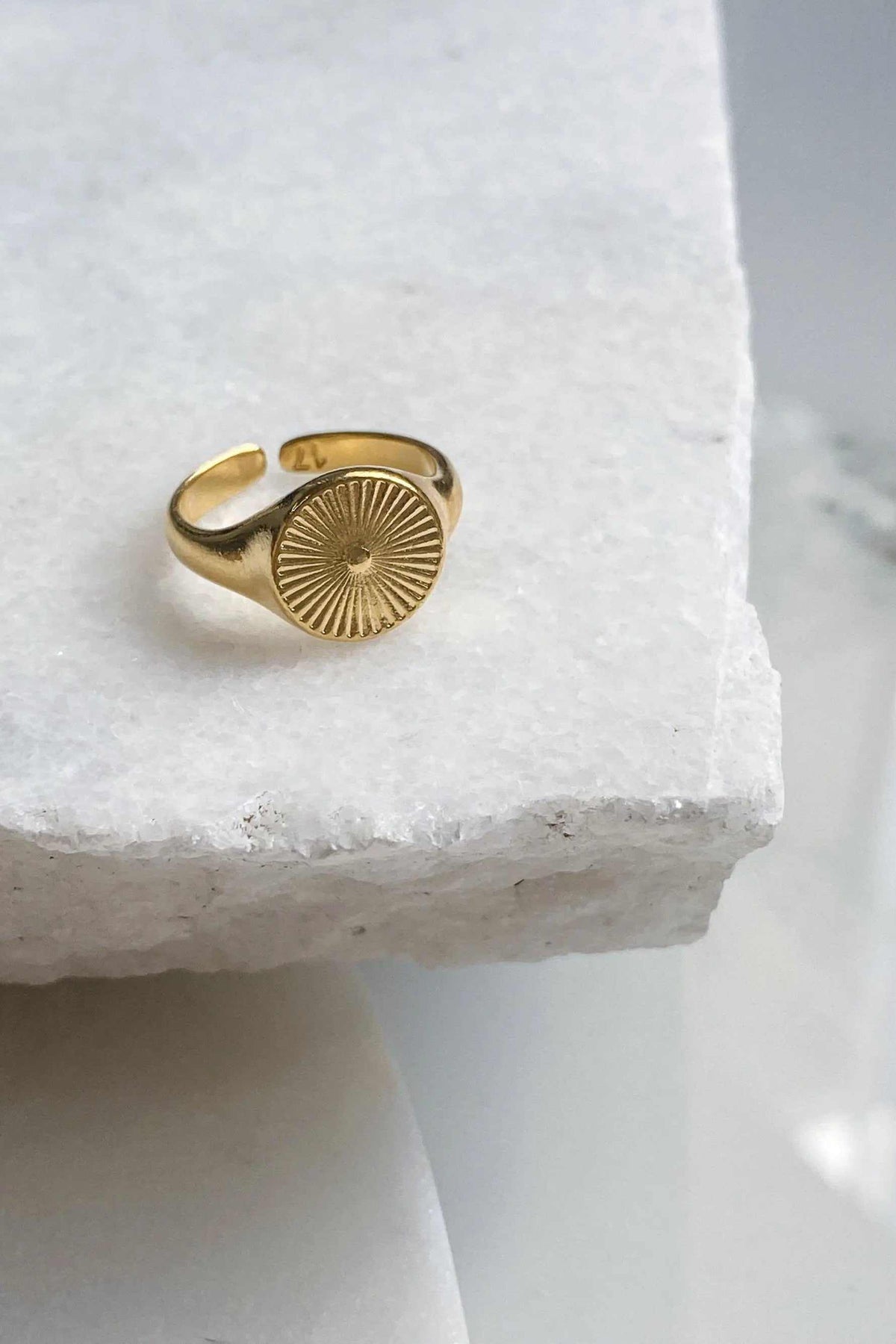 DELOS RING in gold-tone metal with an adjustable open band and round sunburst medallion featuring fine rays