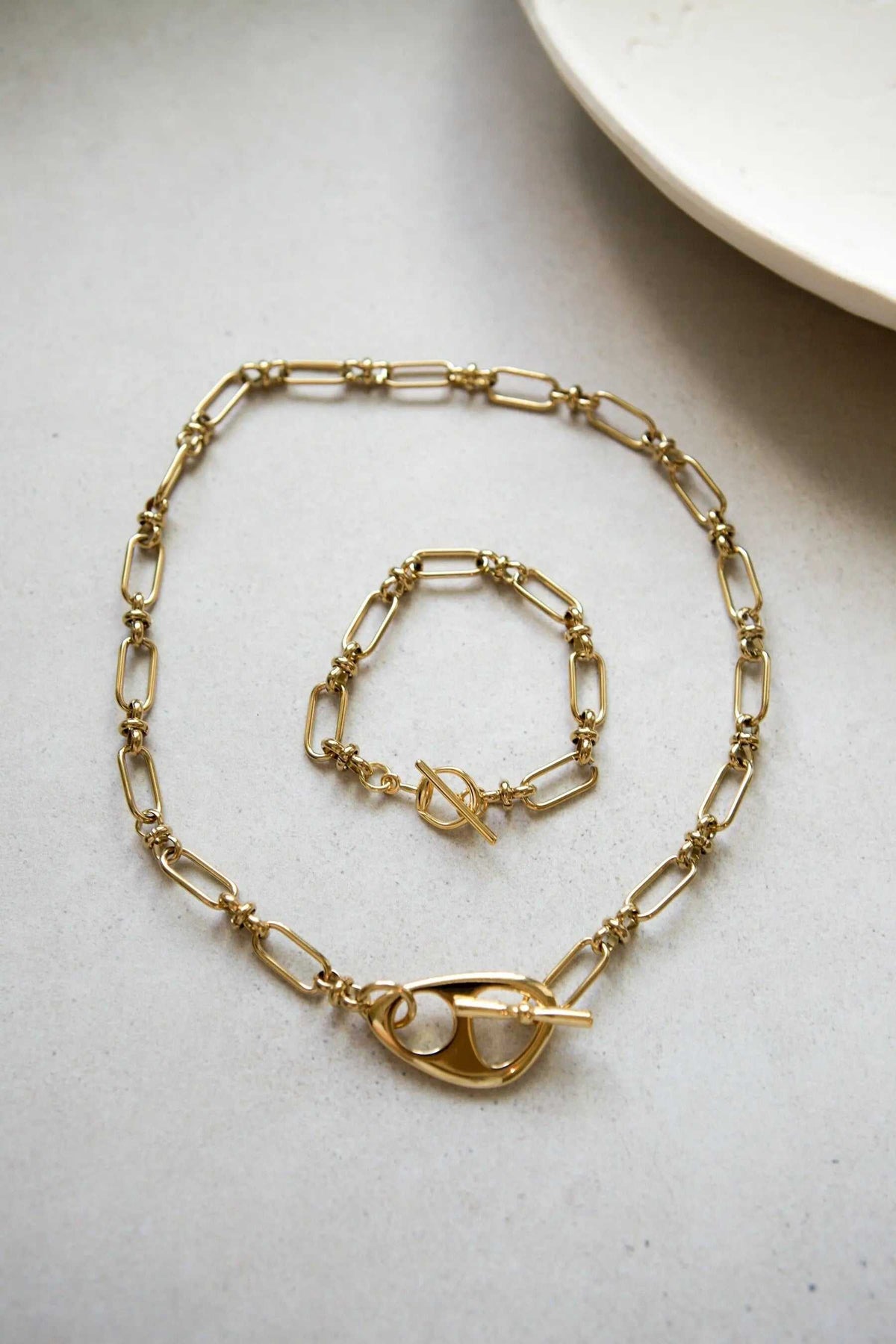 DESMOS Bracelet in gold-tone metal with elongated chain links and a distinctive saddle buckle clasp