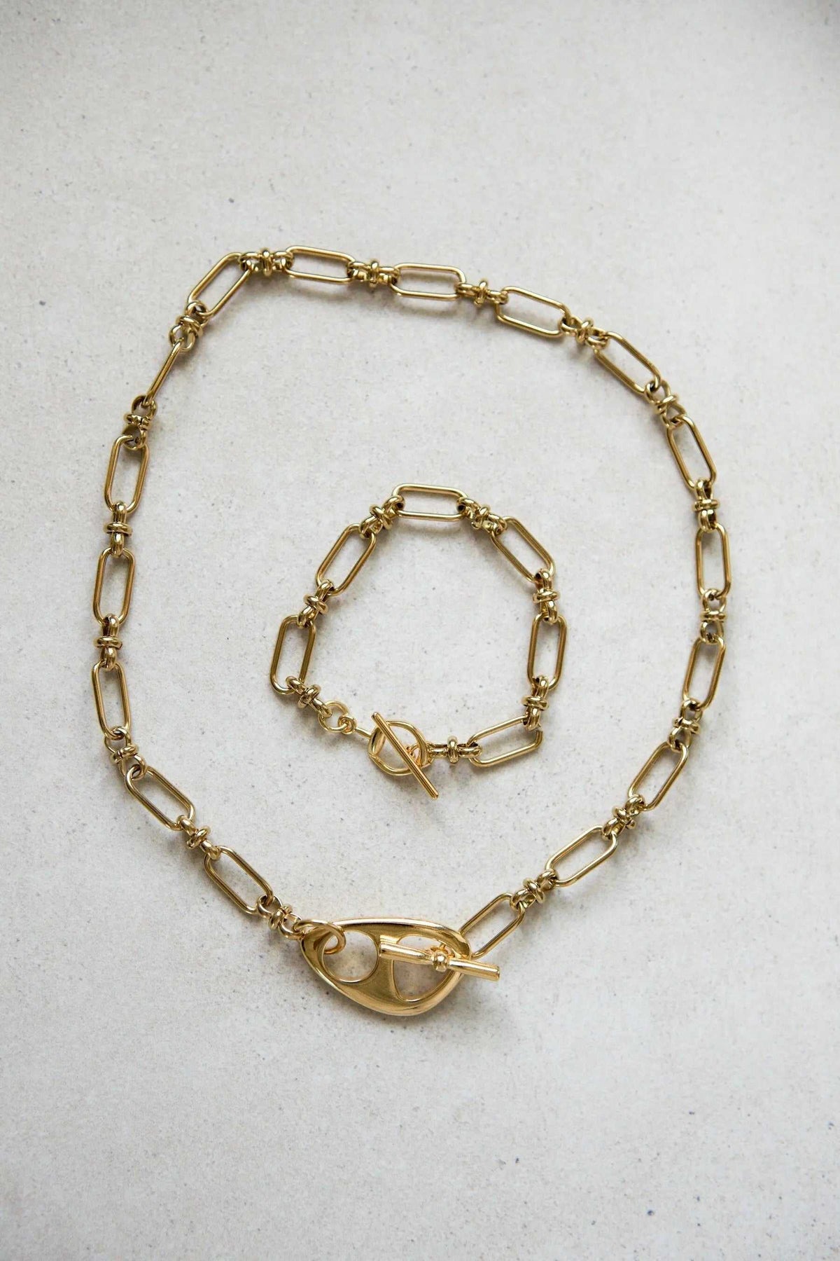 DESMOS Bracelet in gold-tone metal with elongated paperclip links and a prominent saddle-style buckle closure