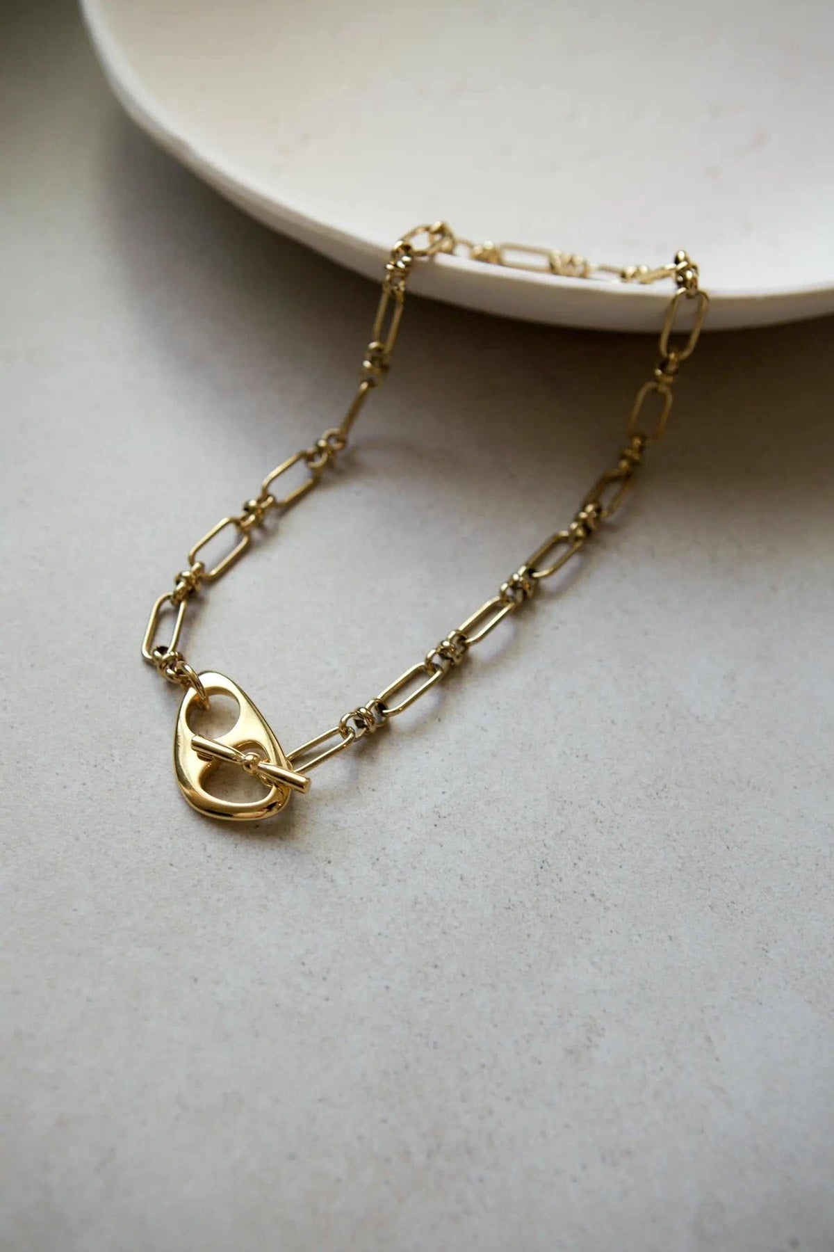 DESMOS Bracelet, gold-tone steel chain with elongated links and a distinctive saddle-shaped buckle clasp.