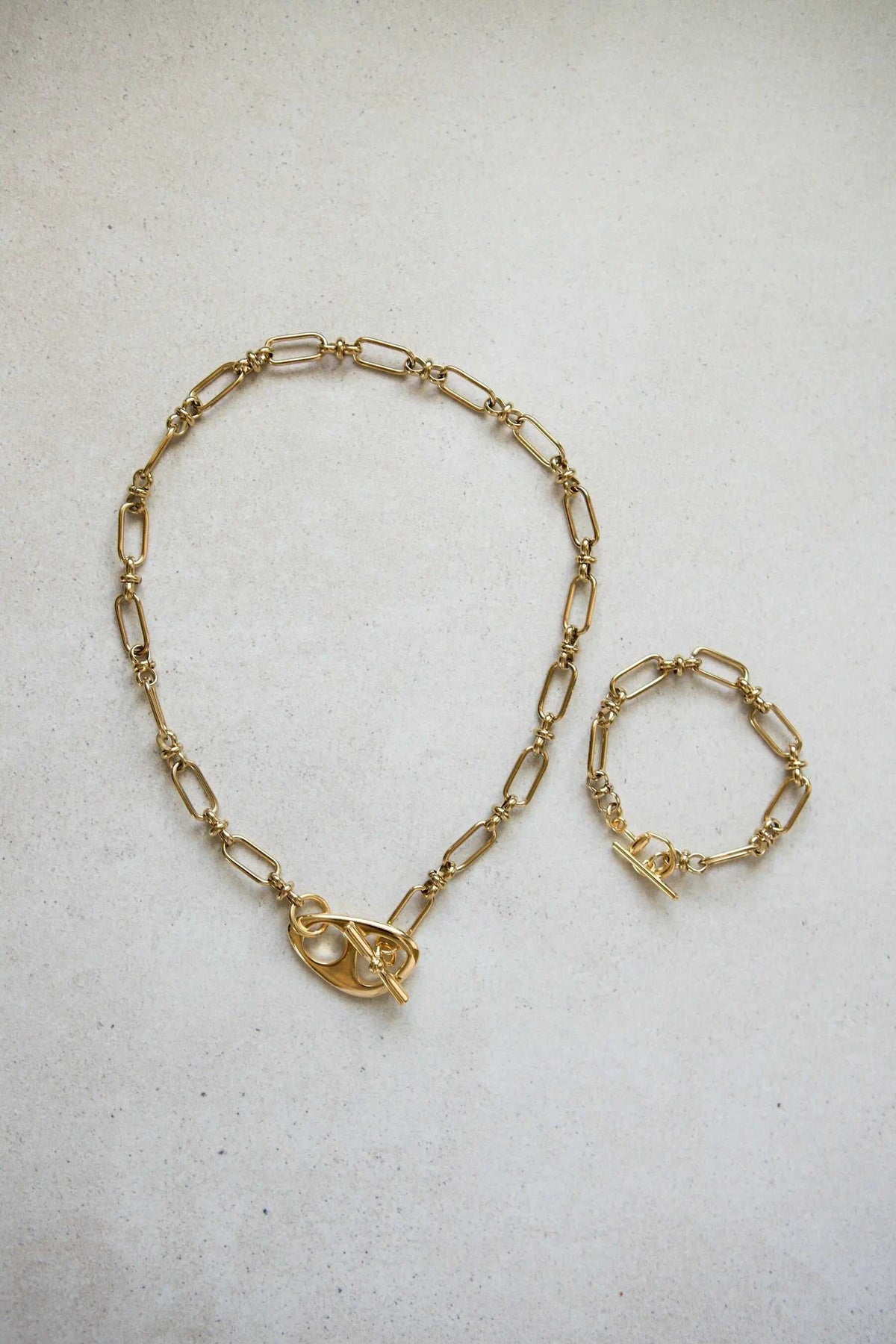 DESMOS Bracelet in gold-tone steel with elongated open chain links and a distinctive saddle buckle clasp