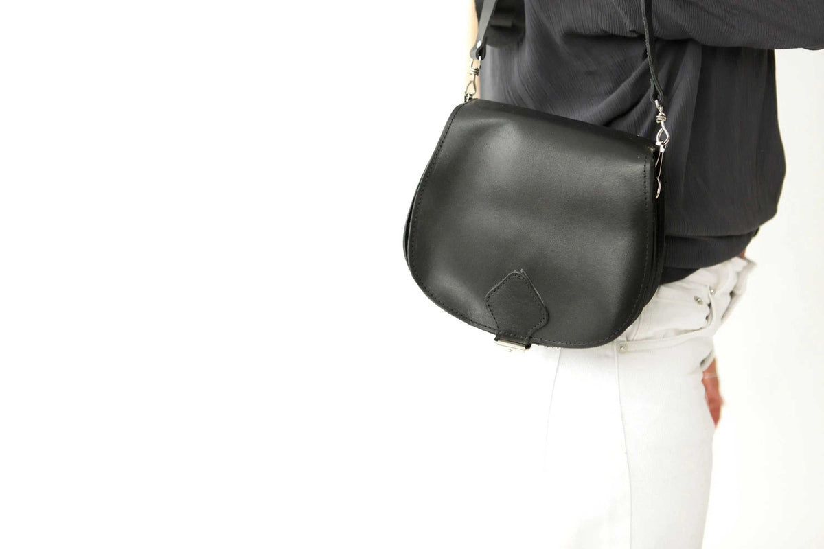 DIONE black full grain leather saddle shoulder bag with rounded shape, adjustable strap and metal buckles