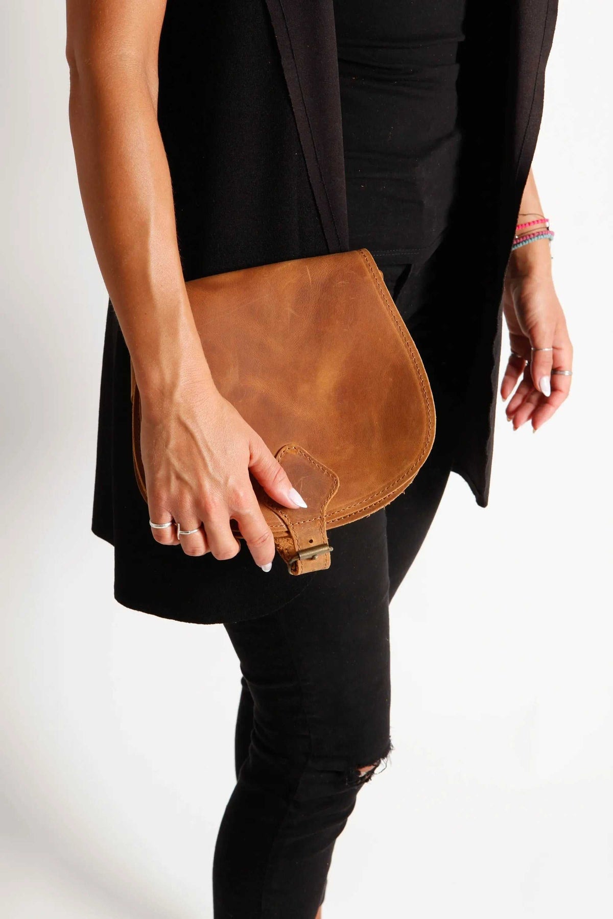 DIONE saddle shoulder bag in natural brown leather with a curved flap, adjustable strap and metal buckle