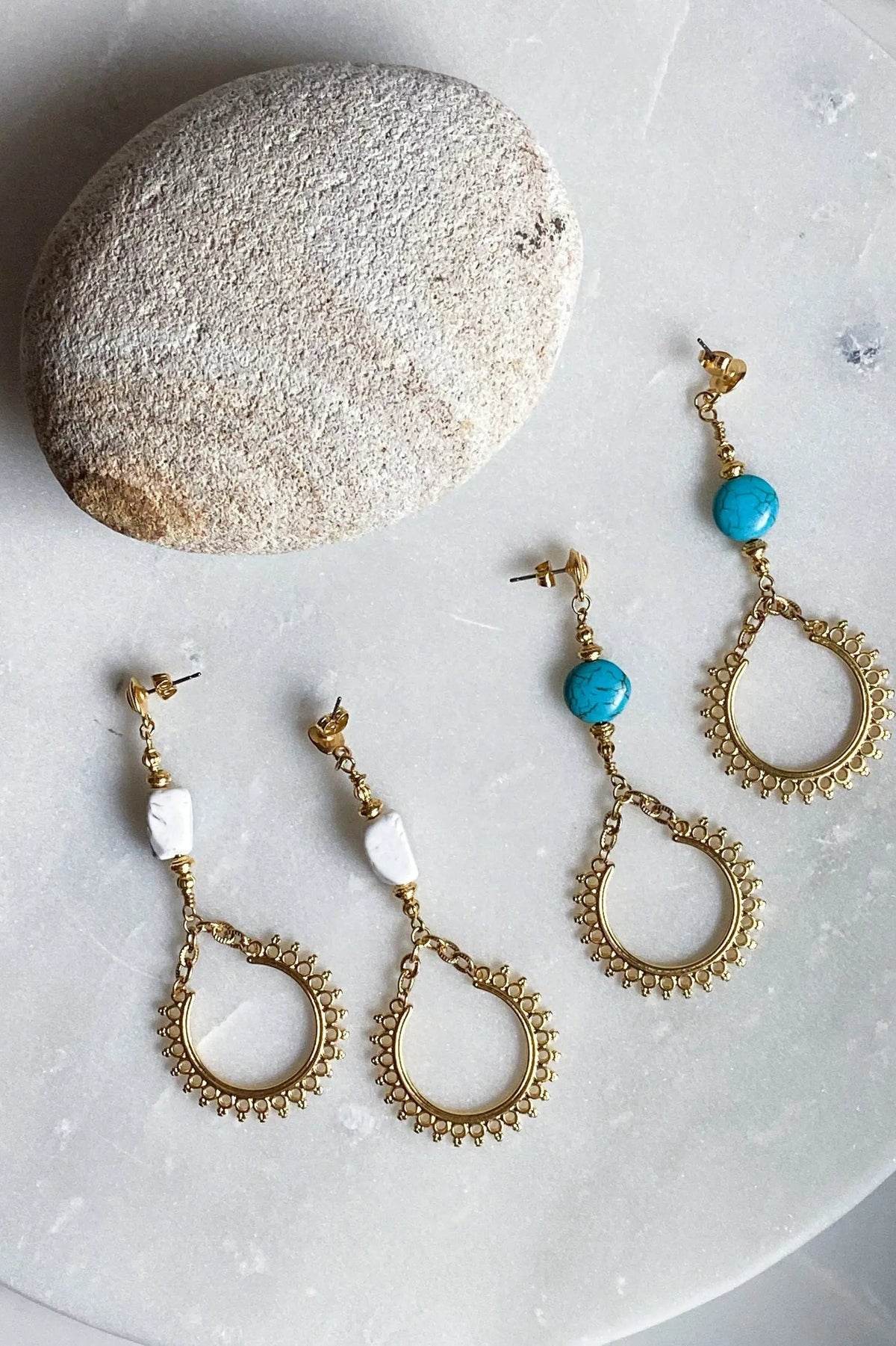 ÉRIS EARRINGS feature gold-tone brass teardrop hoops with beaded edges, one turquoise stone and one white stone pair