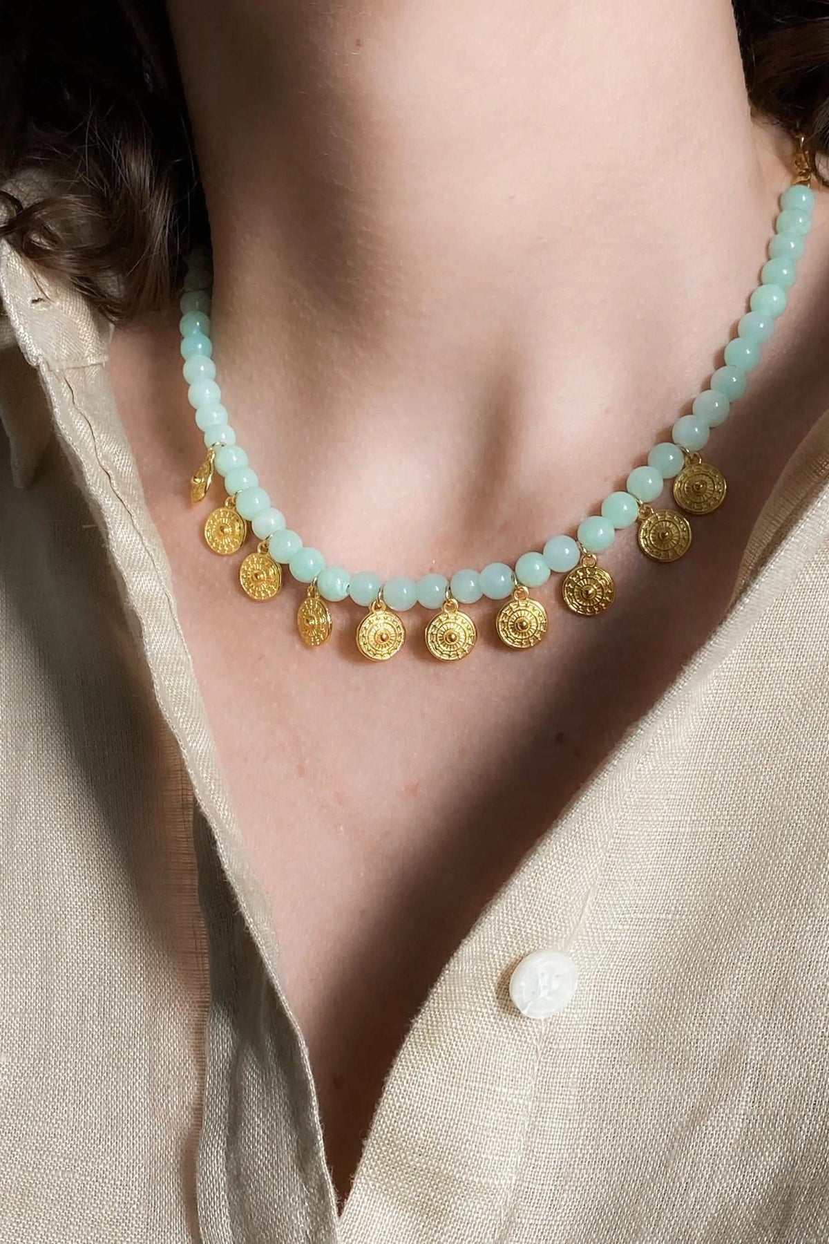 ERSA NECKLACE with pale aqua round beads and small ornate gold-tone coin pendants along the lower edge