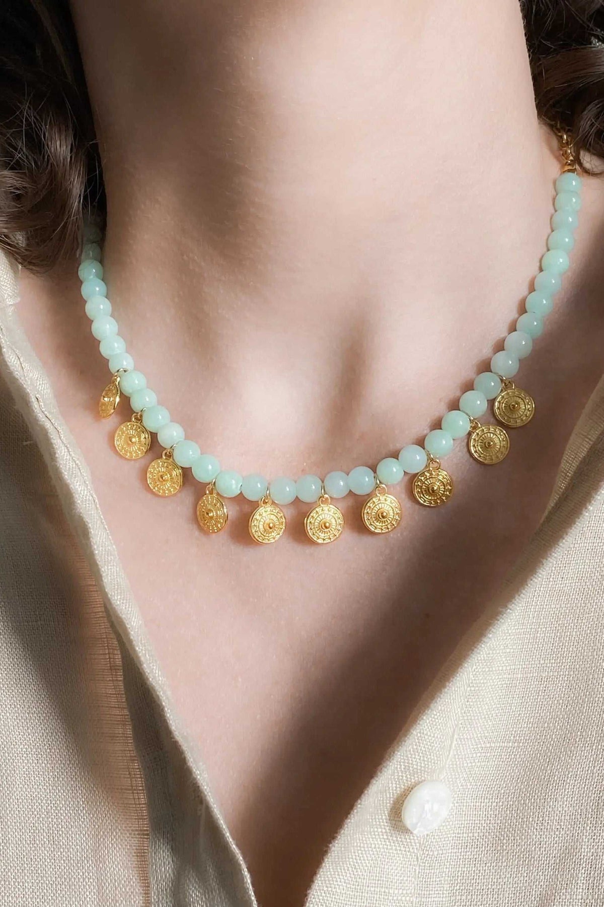 ERSA NECKLACE with pale blue beaded strand and dangling round gold-toned patterned pendants