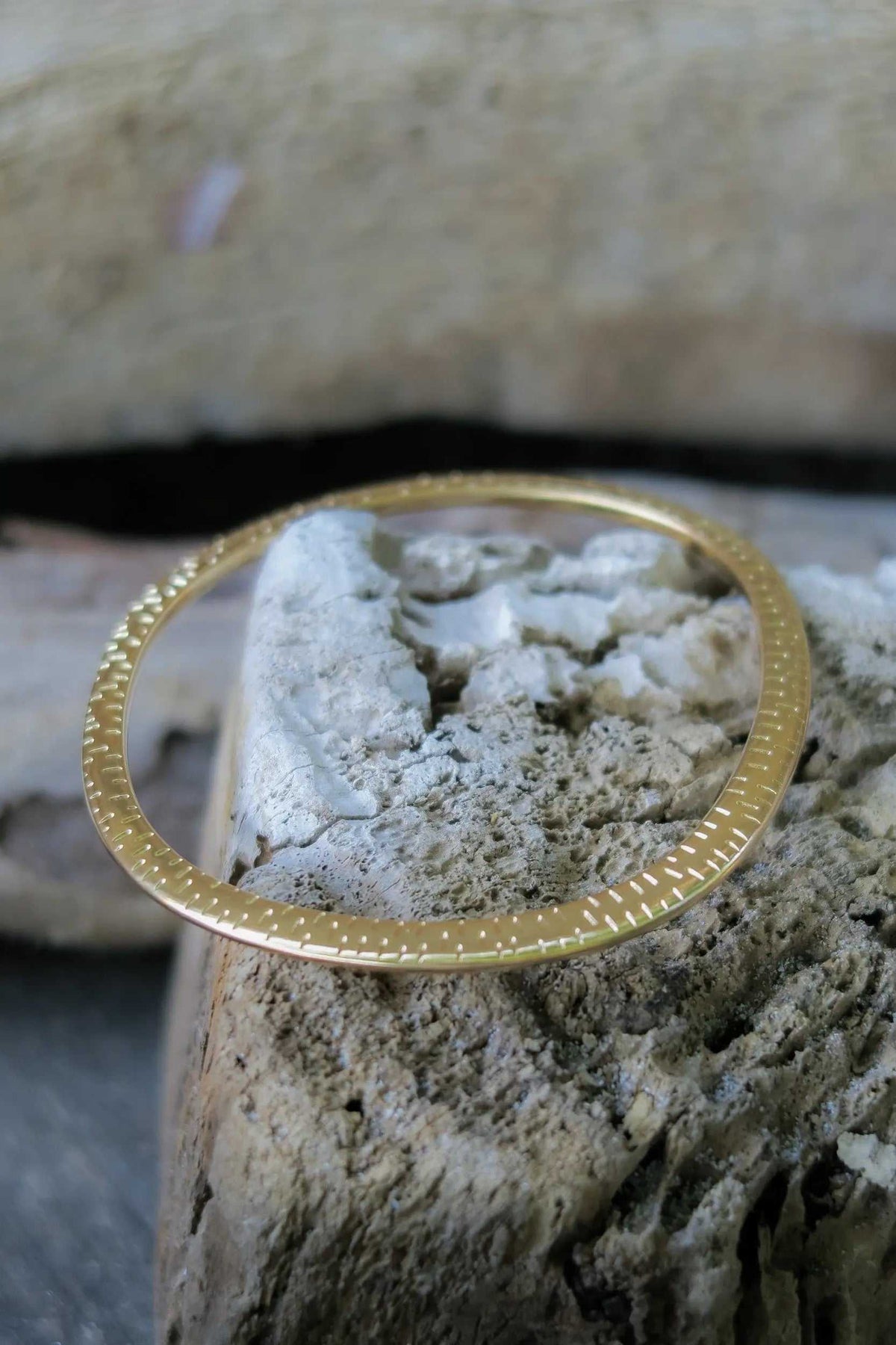 Ethnic Oval bangle in gold-tone metal, with a thin flat oval band and fine dotted detailing along its edge