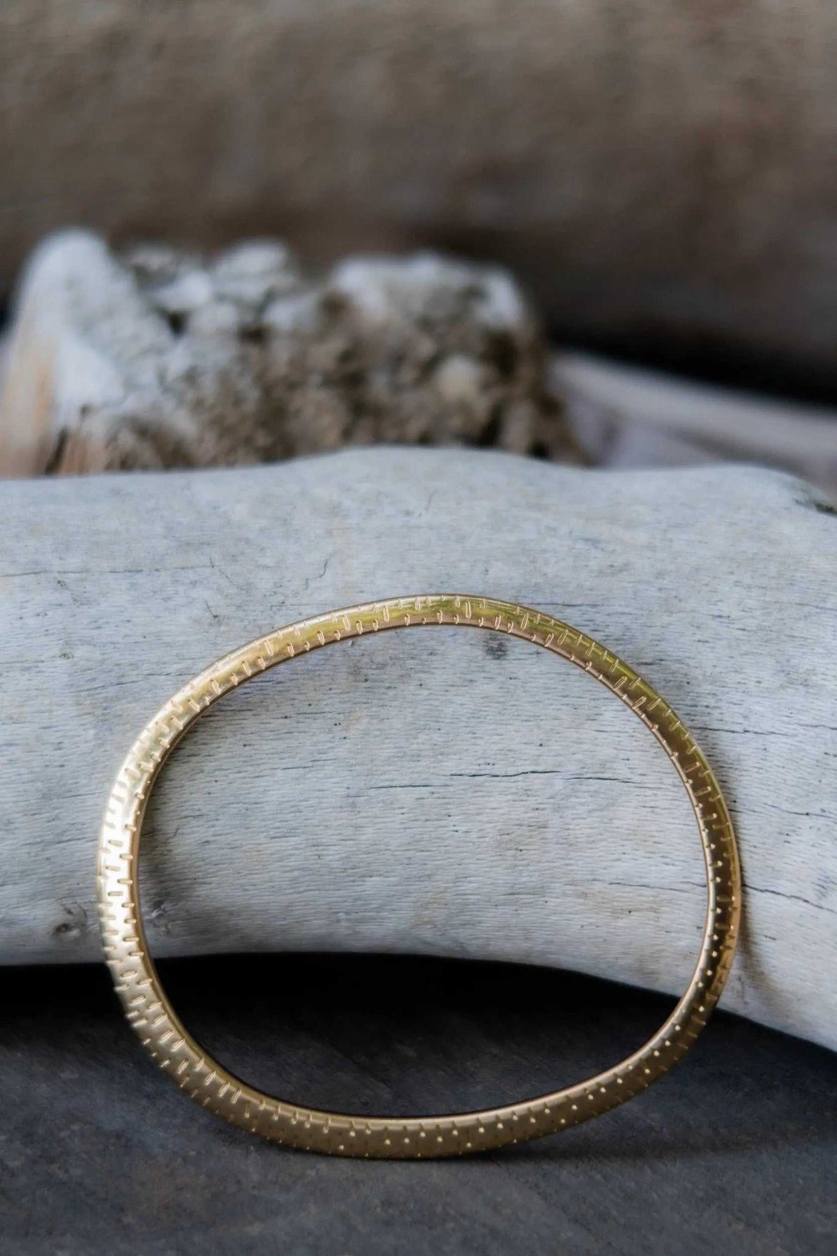 Ethnic Oval bangle in gold-tone metal, thin and flat with an oval shape and finely textured dotted detailing.