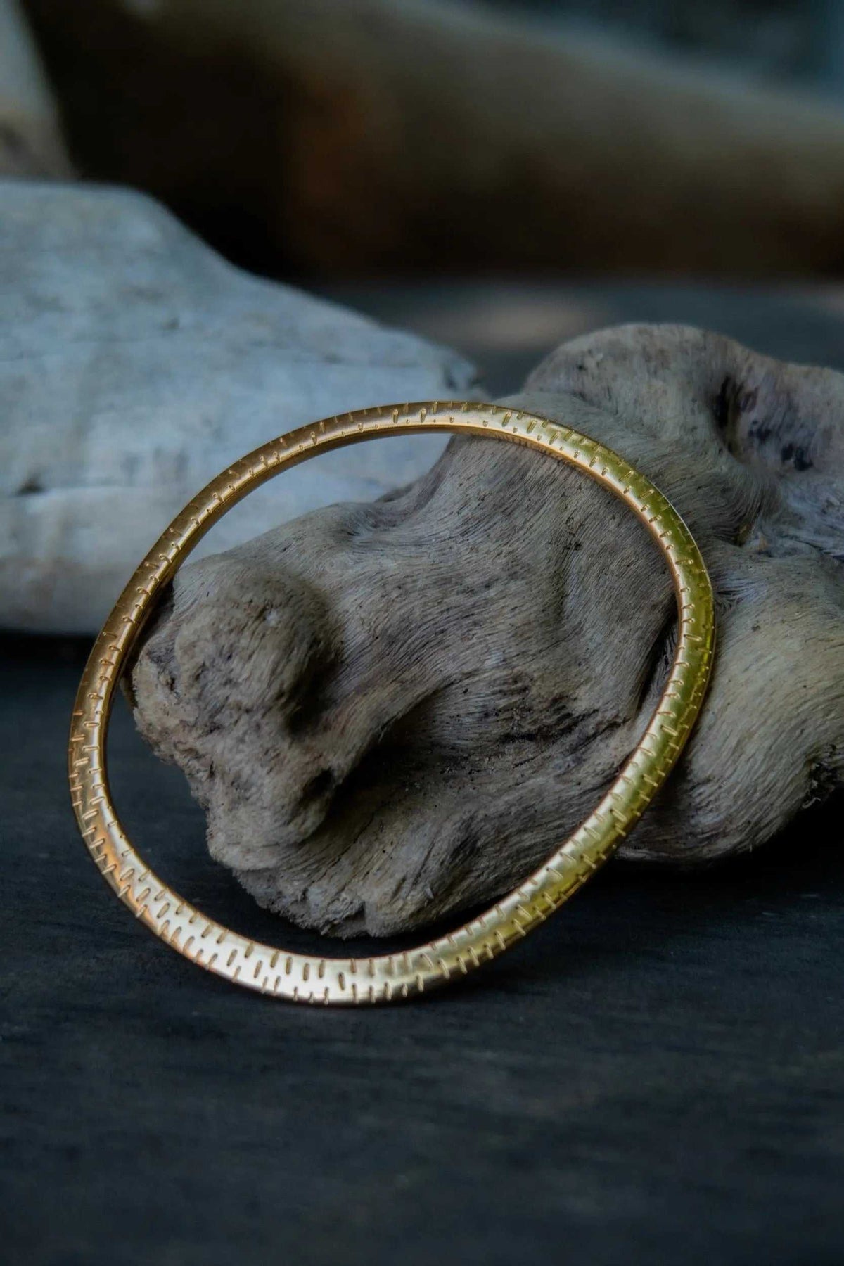Ethnic Oval bangle in gold-tone metal with a slim oval shape and textured engraved detailing around the band