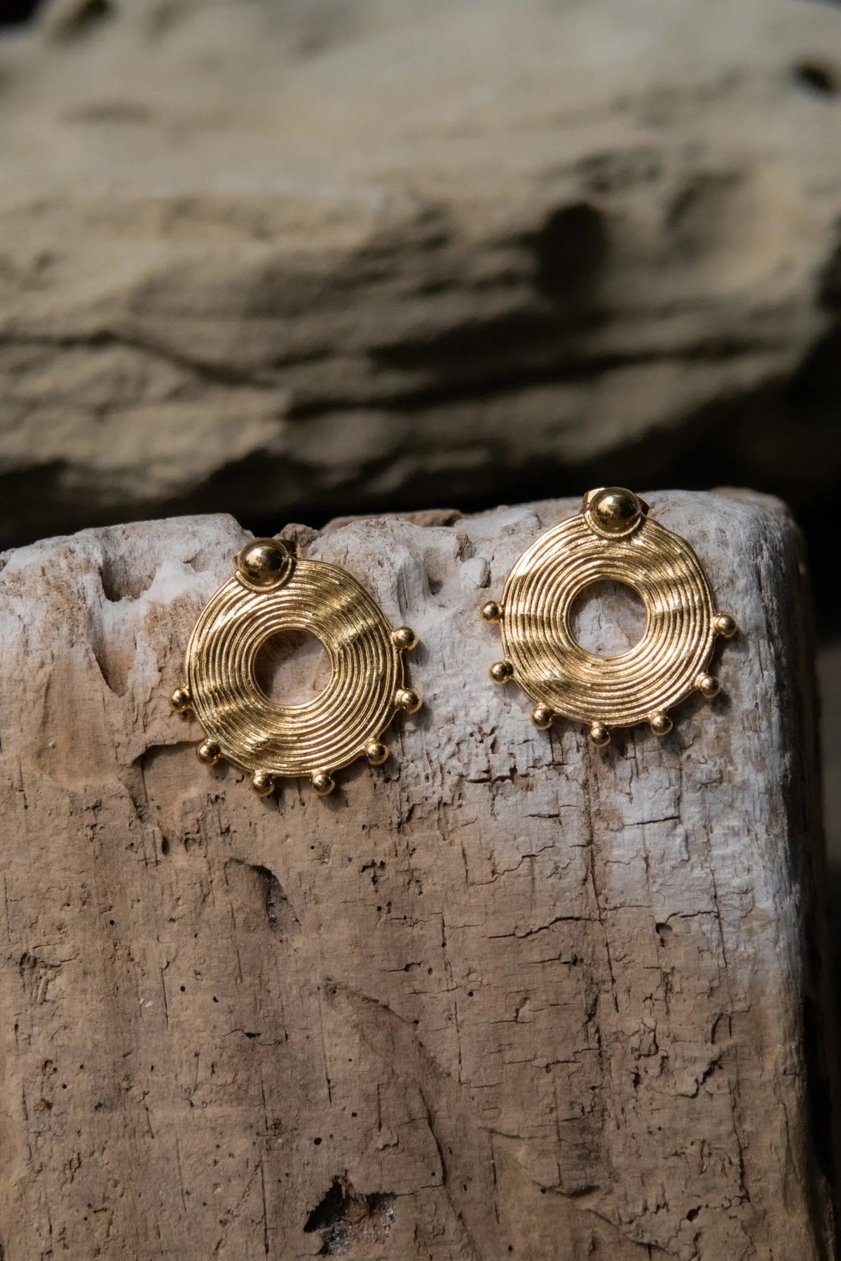 Ethnic round Earrings in gold-tone metal with concentric circular ridges, open centers, and small bead accents around the edges