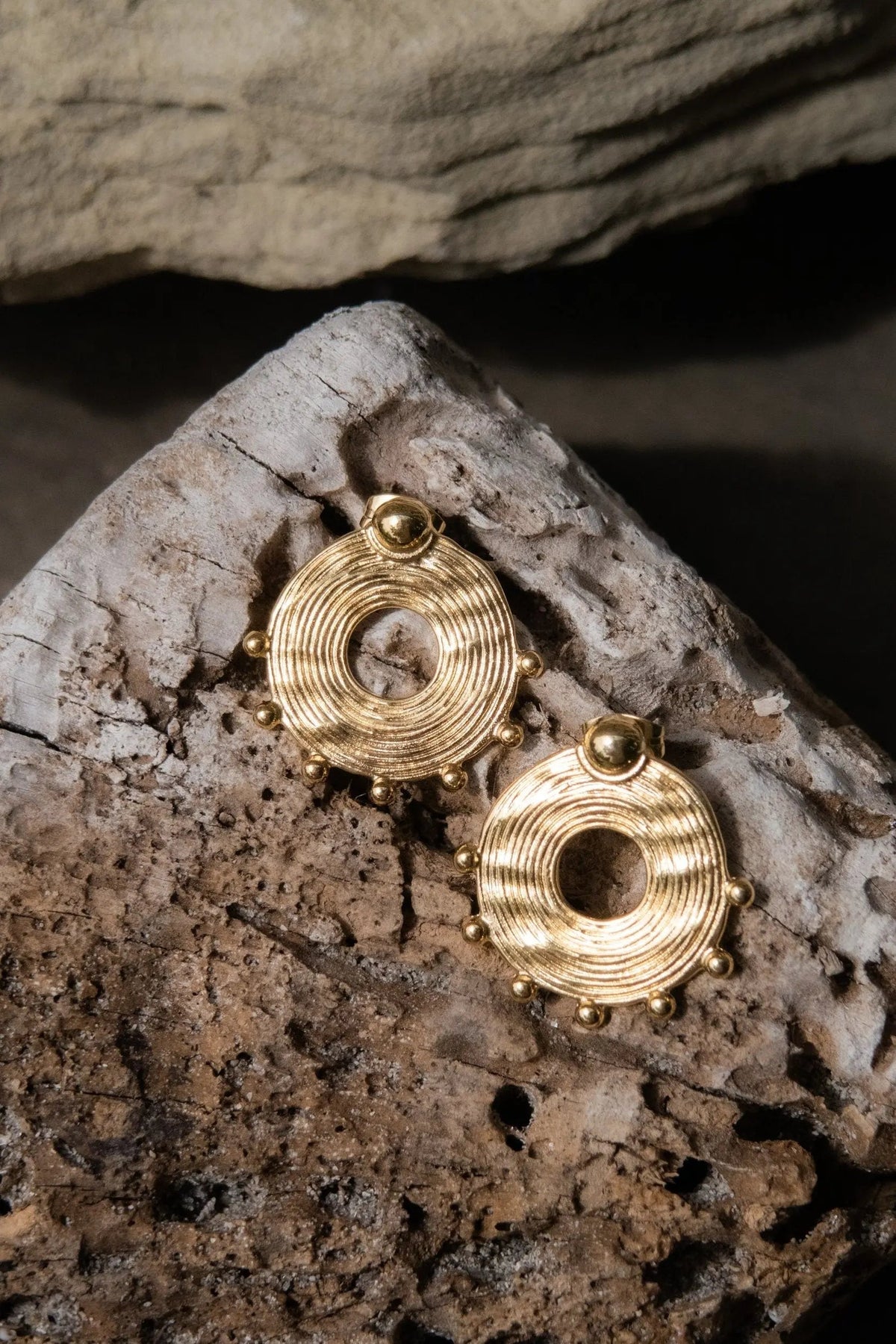 Ethnic round Earrings in gold-tone metal, featuring concentric ridges, open circular centers and small beaded accents.