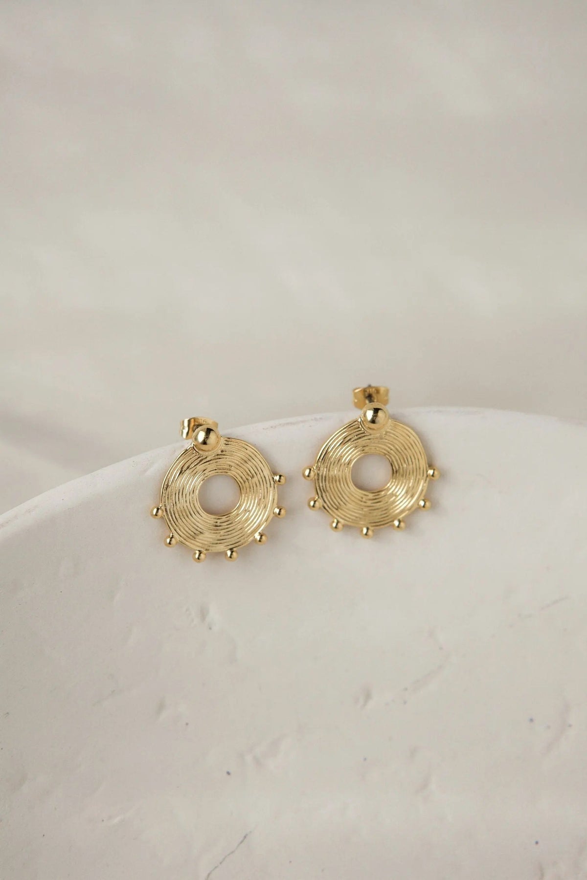 Ethnic round Earrings in gold-tone metal, featuring textured concentric rings and small decorative bead accents
