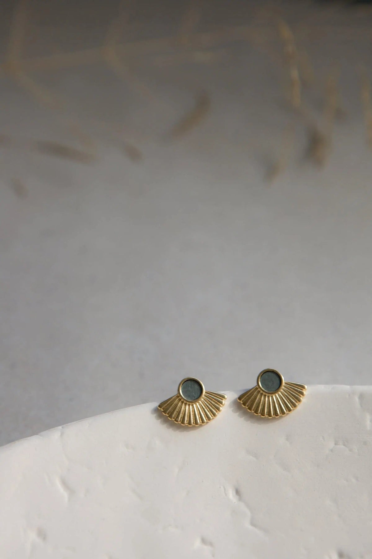 Ethnic stud earrings with grey resin centers and gold-tone brass fan-shaped rays in a textured sunburst design