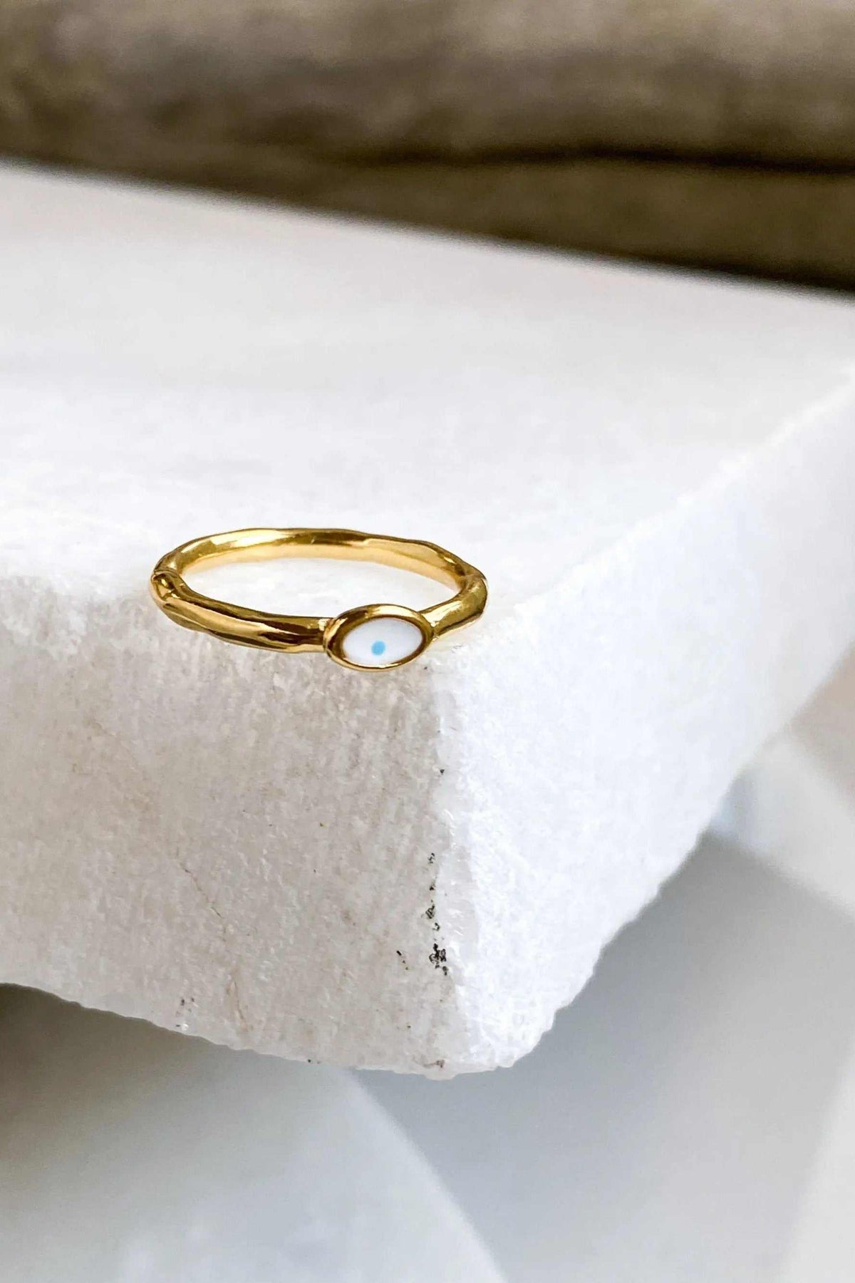 EYE Evil eye ring with a slim gold-tone band and a small oval white eye charm accented by a blue centre