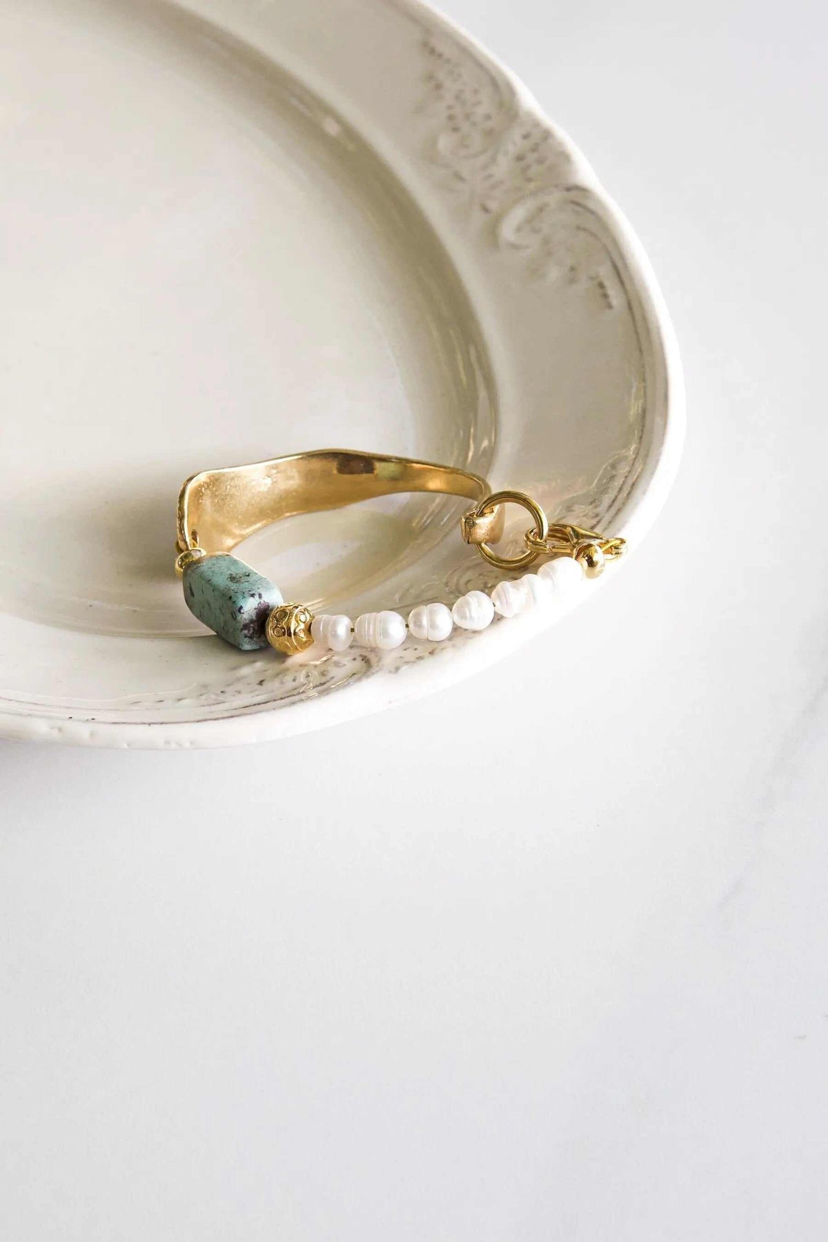 Freshwater Pearl bracelet with white pearls, a pale green stone, gold-tone beads, and a wide polished gold cuff