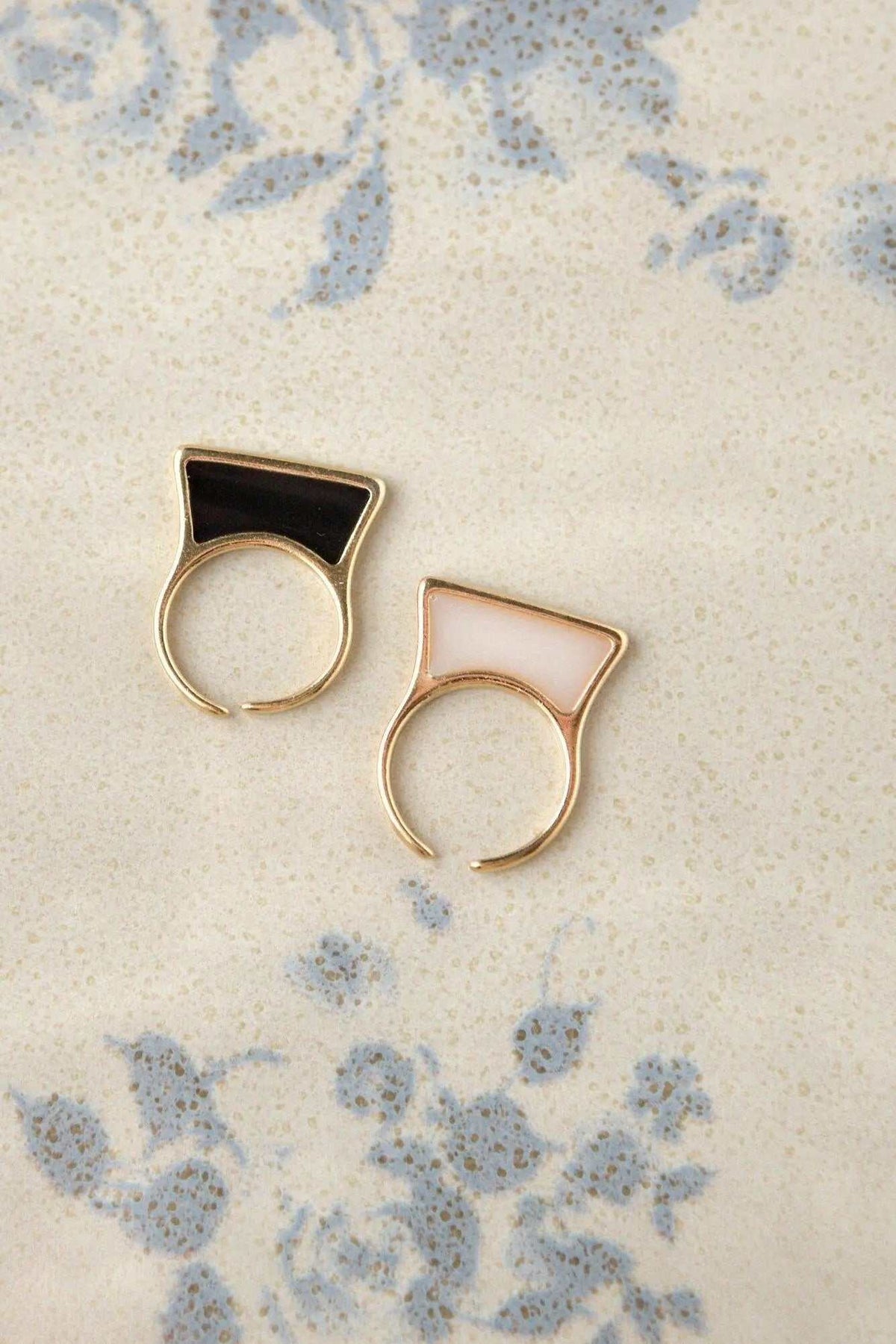 Geometric modern ring pair in gold-tone metal with black and pale pink rectangular stained glass tops and open bands