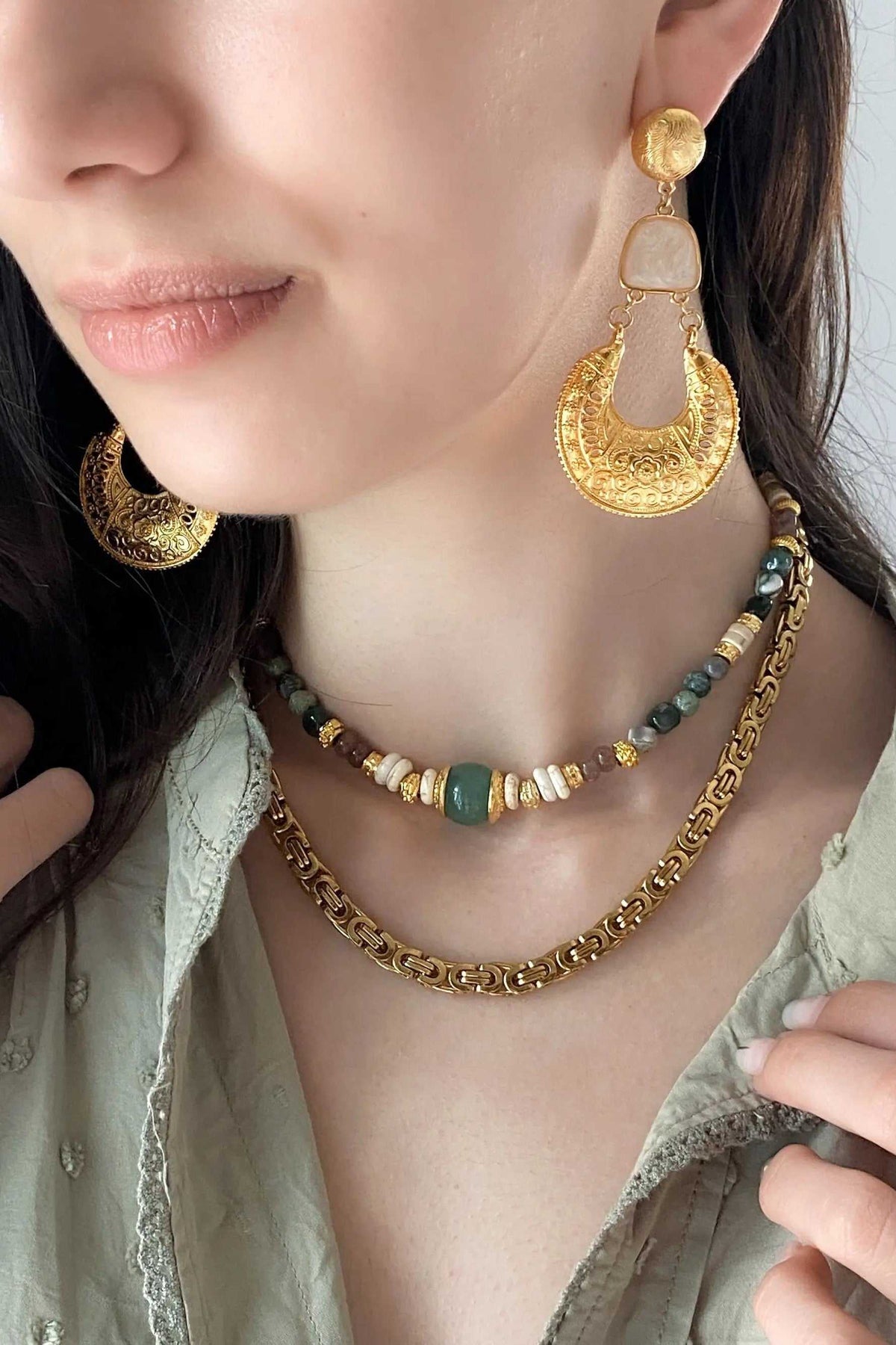 Gold Boho earrings with ornate crescent-shaped filigree drops, round studs and pale geometric connectors in a layered design