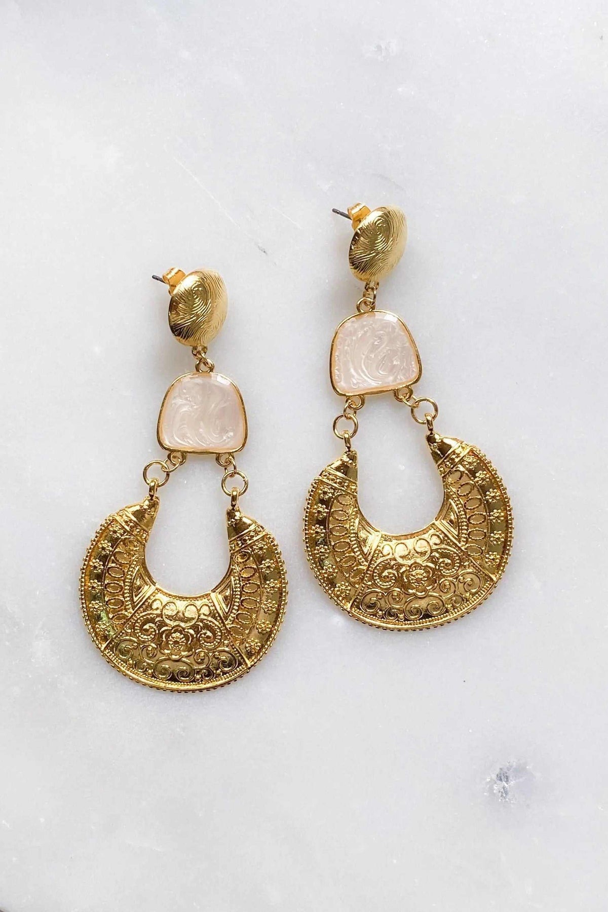 Gold Boho earrings with ornate gold-tone crescent drops, pale pink square accents, and textured round stud tops.
