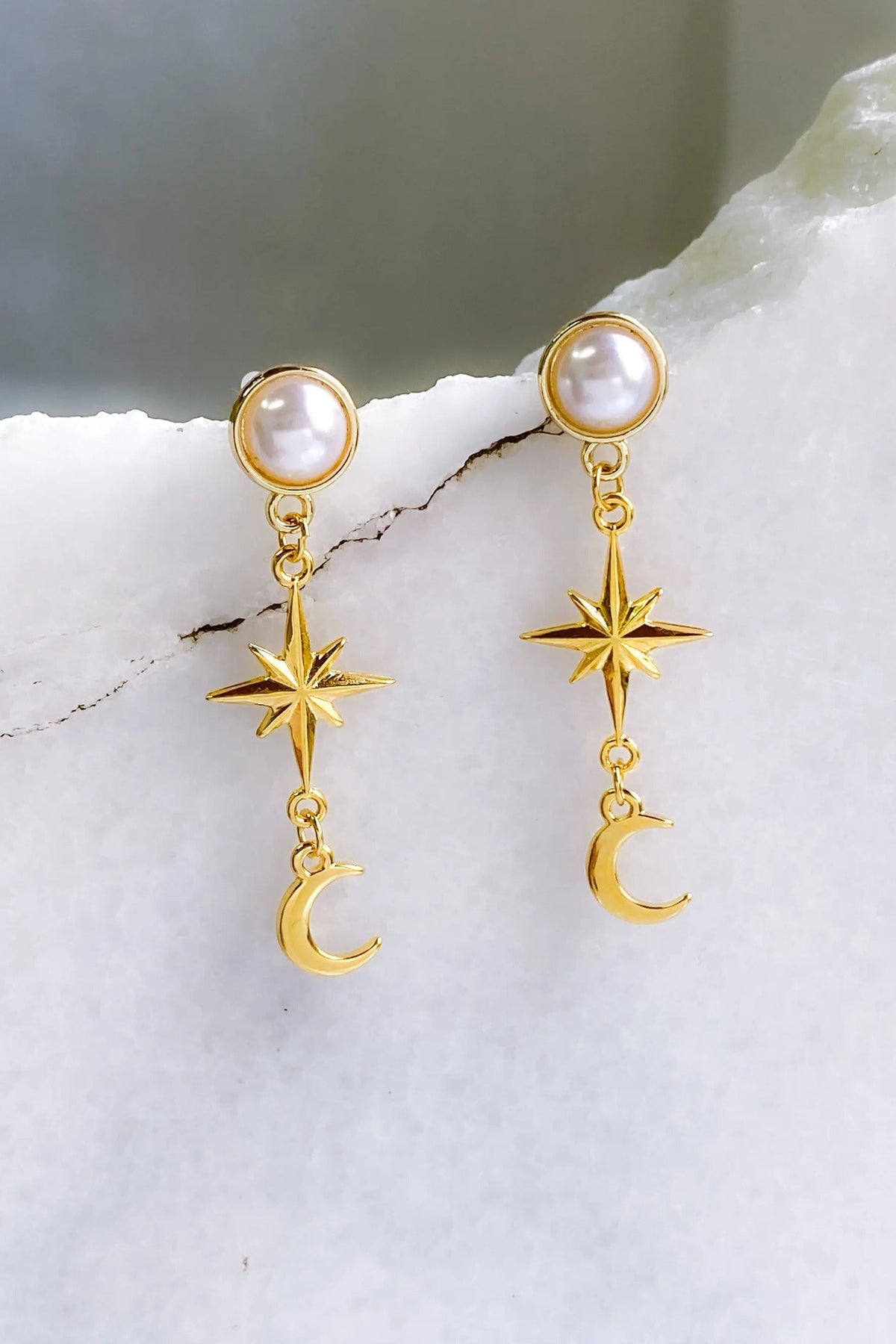 Gold celestial Earrings with white pearl studs, gold-tone dangling starbursts and crescent moons in a delicate design