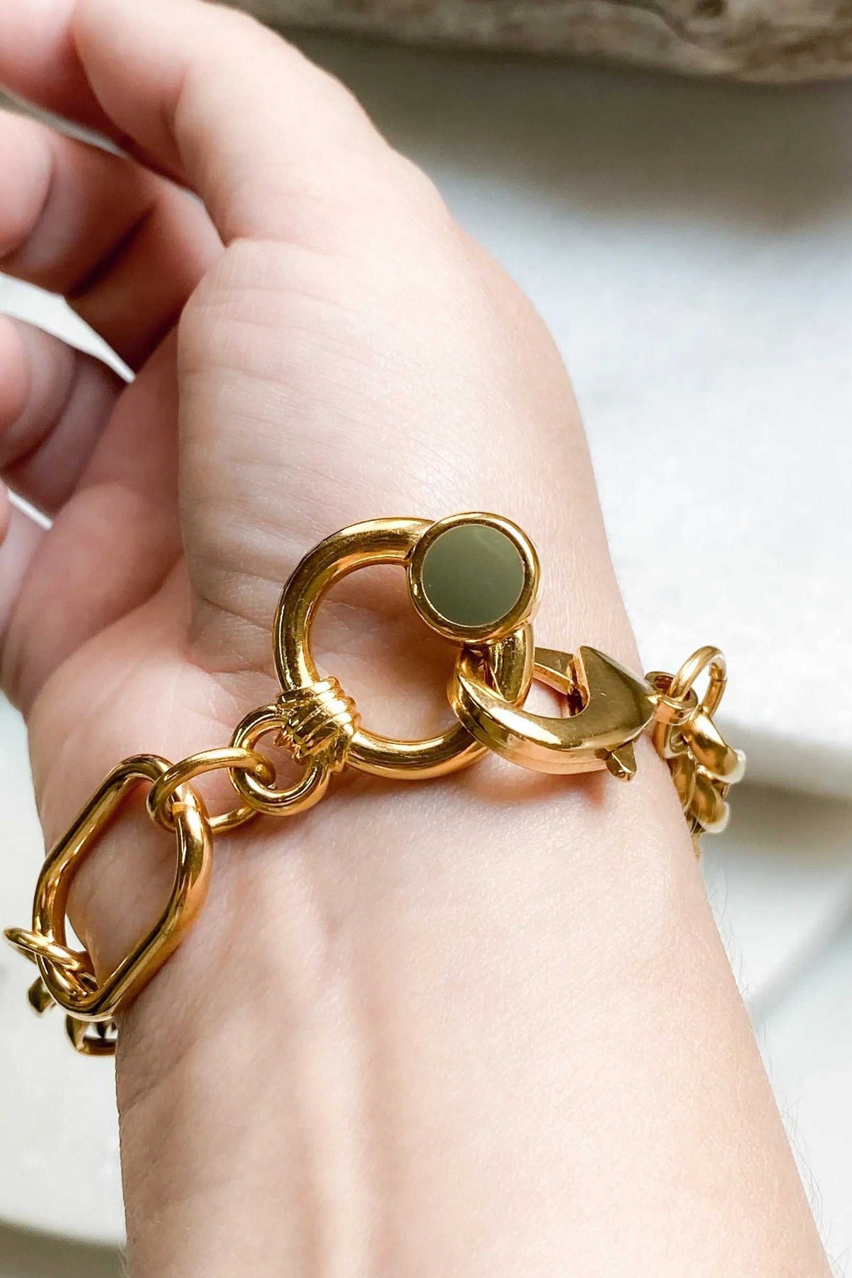 Gold Chain bracelet in polished gold-tone metal, featuring chunky interlocking links and a round dark green clasp accent