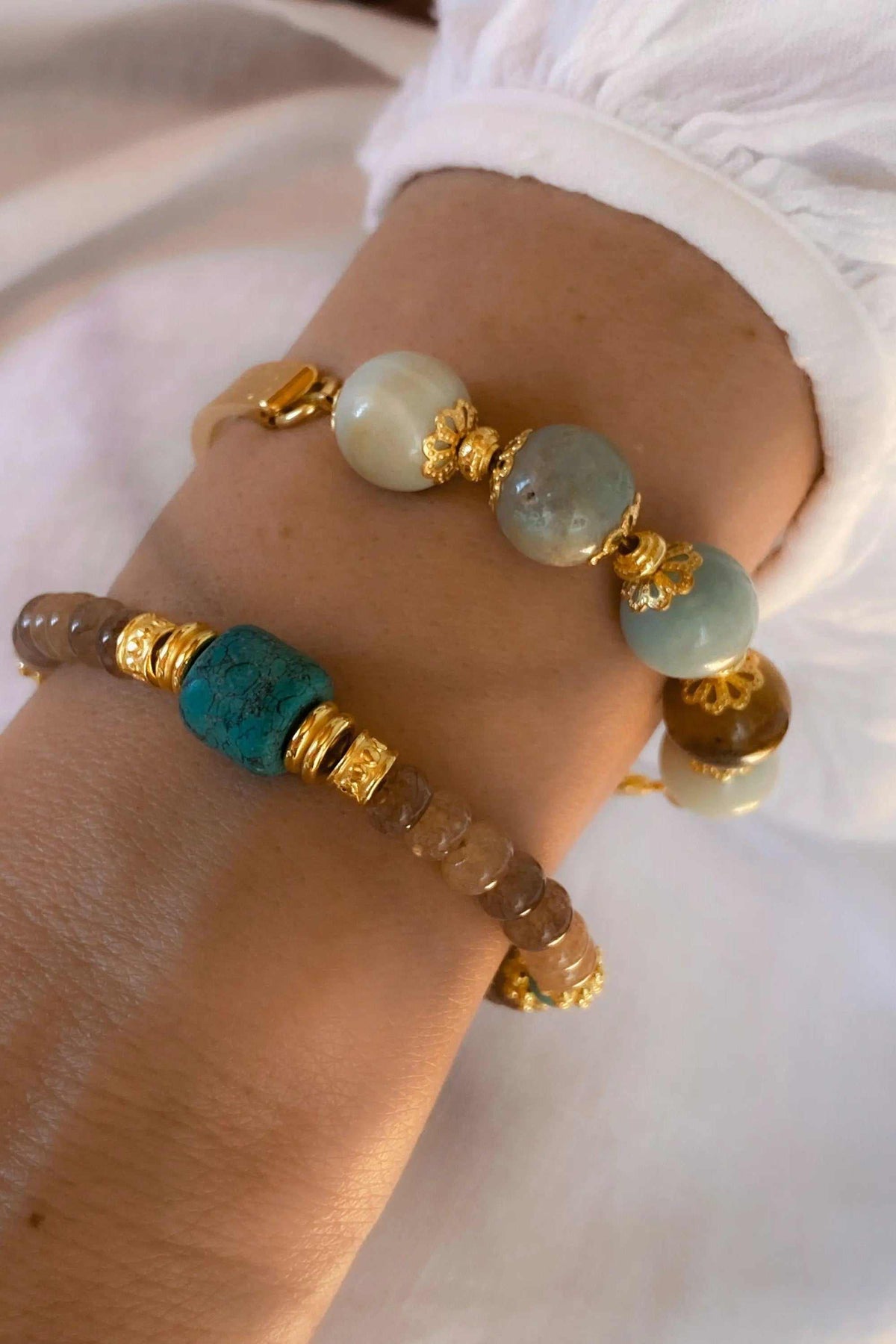 Gold cuff bracelet with pale blue and gray amazonite beads, gold-toned floral spacers and a gold-plated clasp
