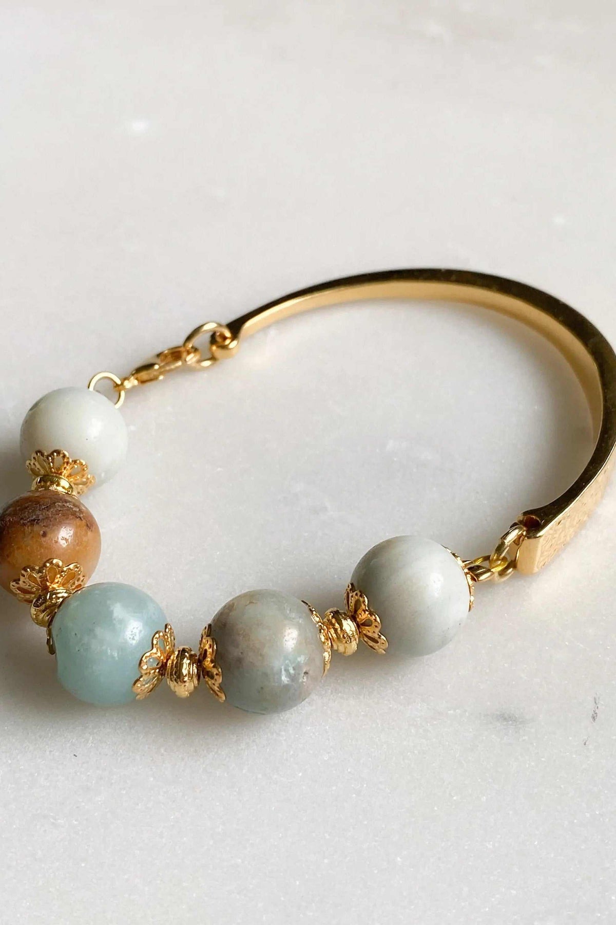 Gold cuff bracelet with polished gold-tone metal, pale multicolor amazonite beads and ornate floral spacers