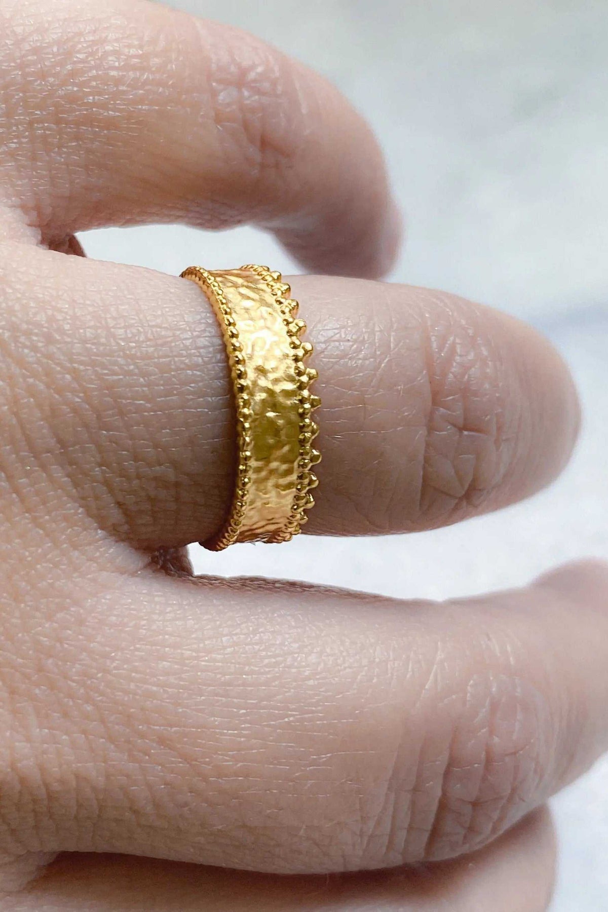 Gold dainty ring in a warm gold-tone metal with a textured center and delicate scalloped lace-like edges