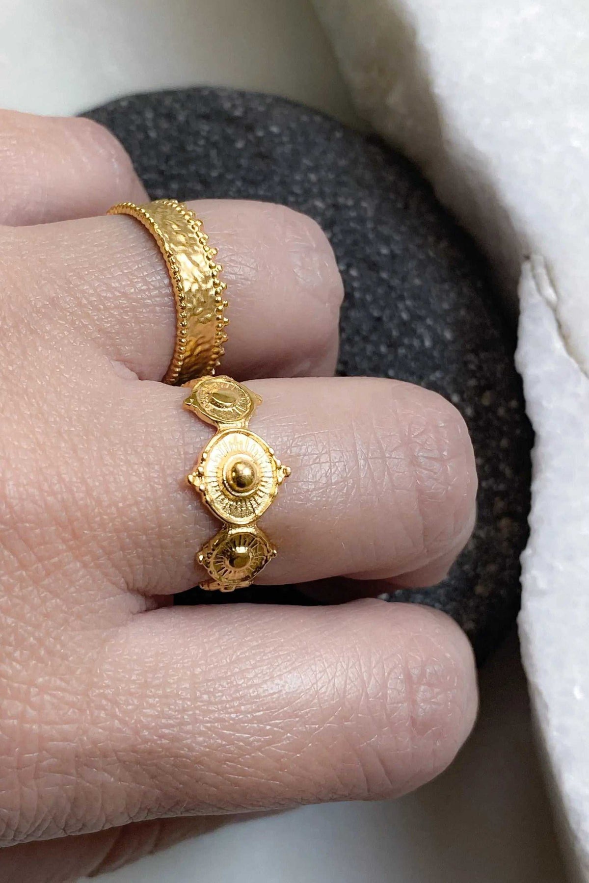 Gold dainty ring with a textured band, delicate beaded edges, and three ornate oval gold motifs